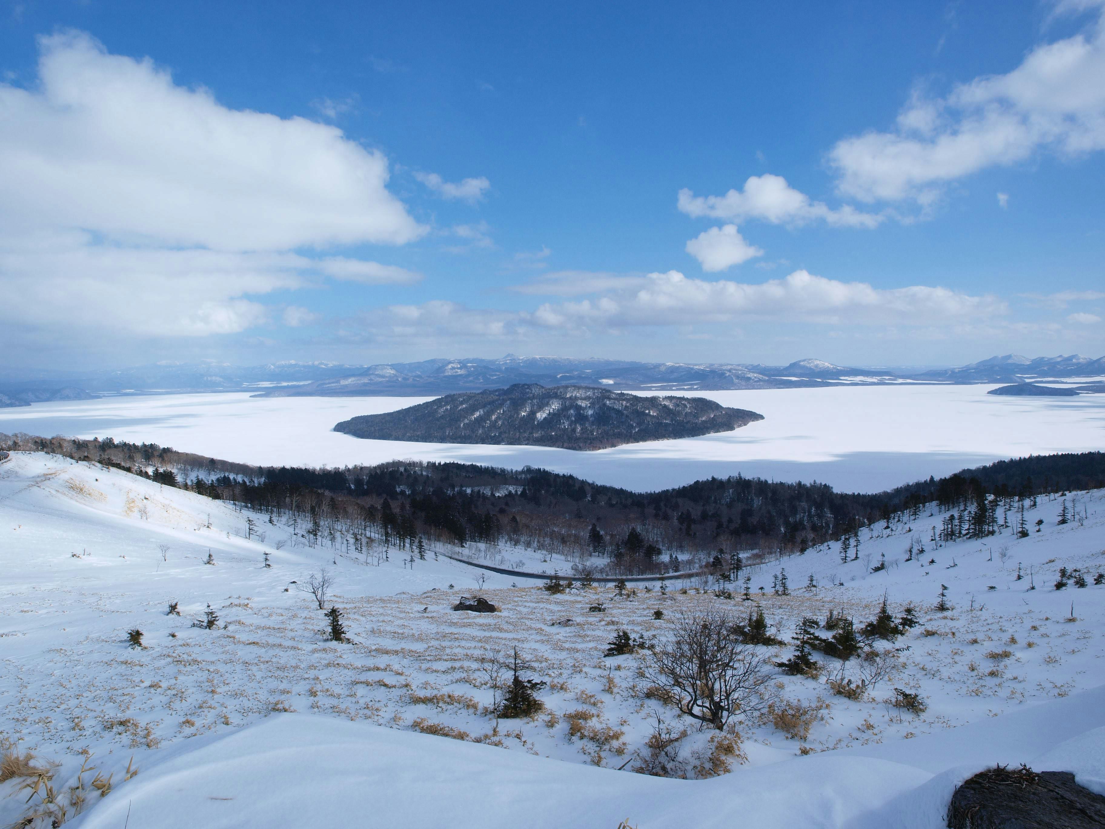 雪原と湖を見下ろす山並みの風景