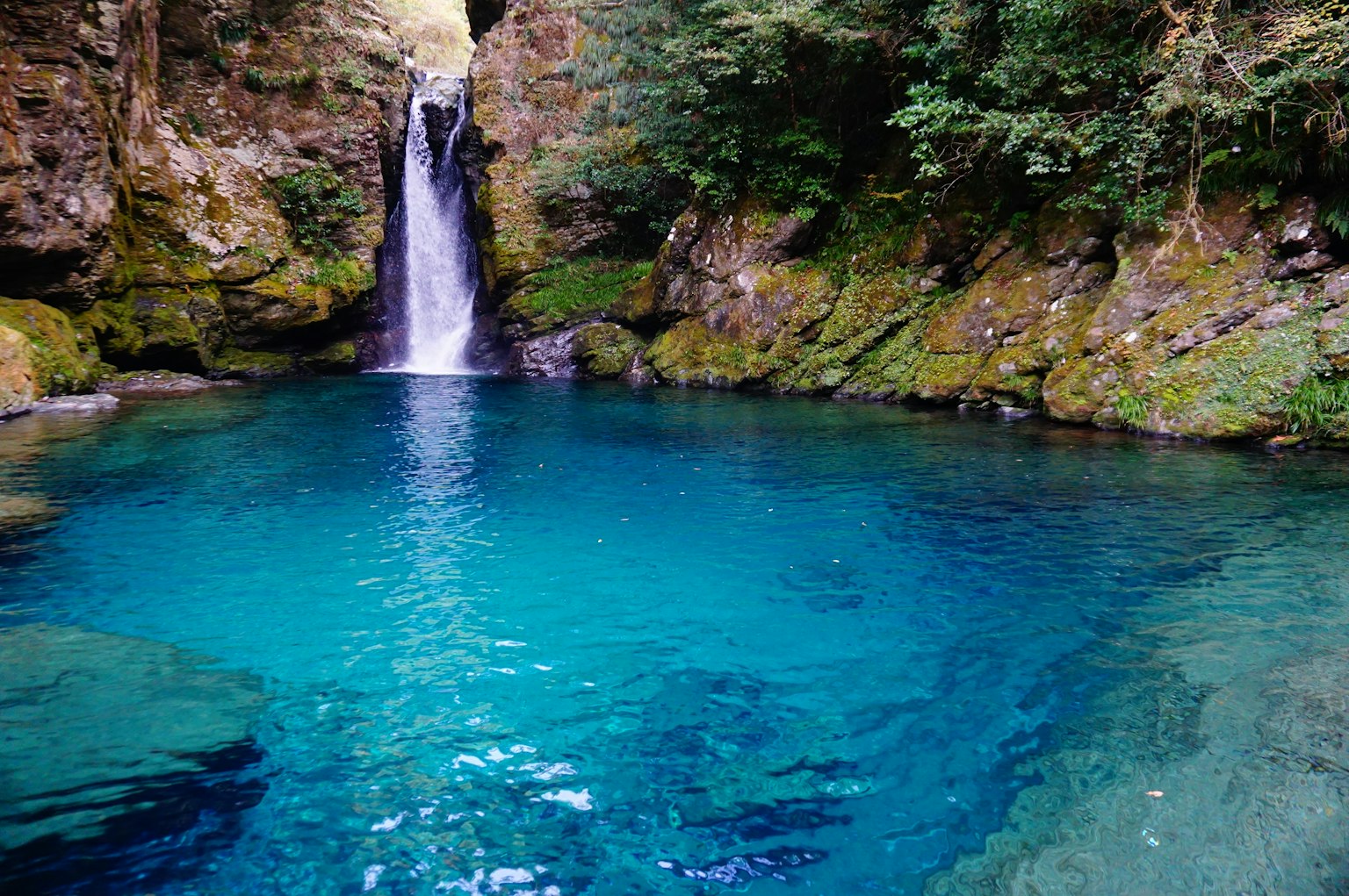 Eine ruhige Naturszene mit einem schönen blauen Pool und einem Wasserfall
