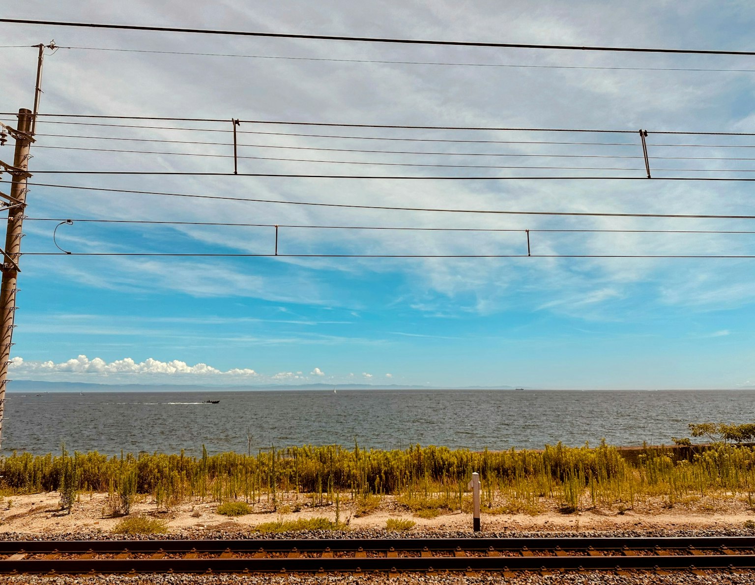 Railway view with blue sky and sea background featuring railway tracks and grass