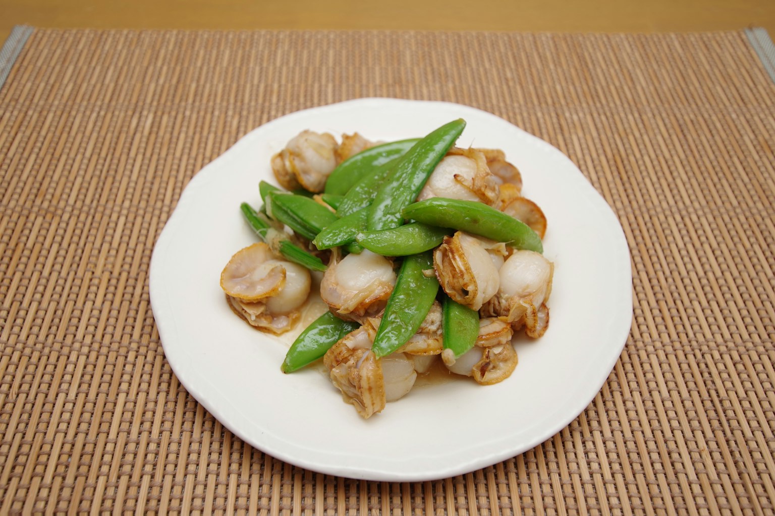 Hidangan kerang scallop dan kacang polong manis di piring putih