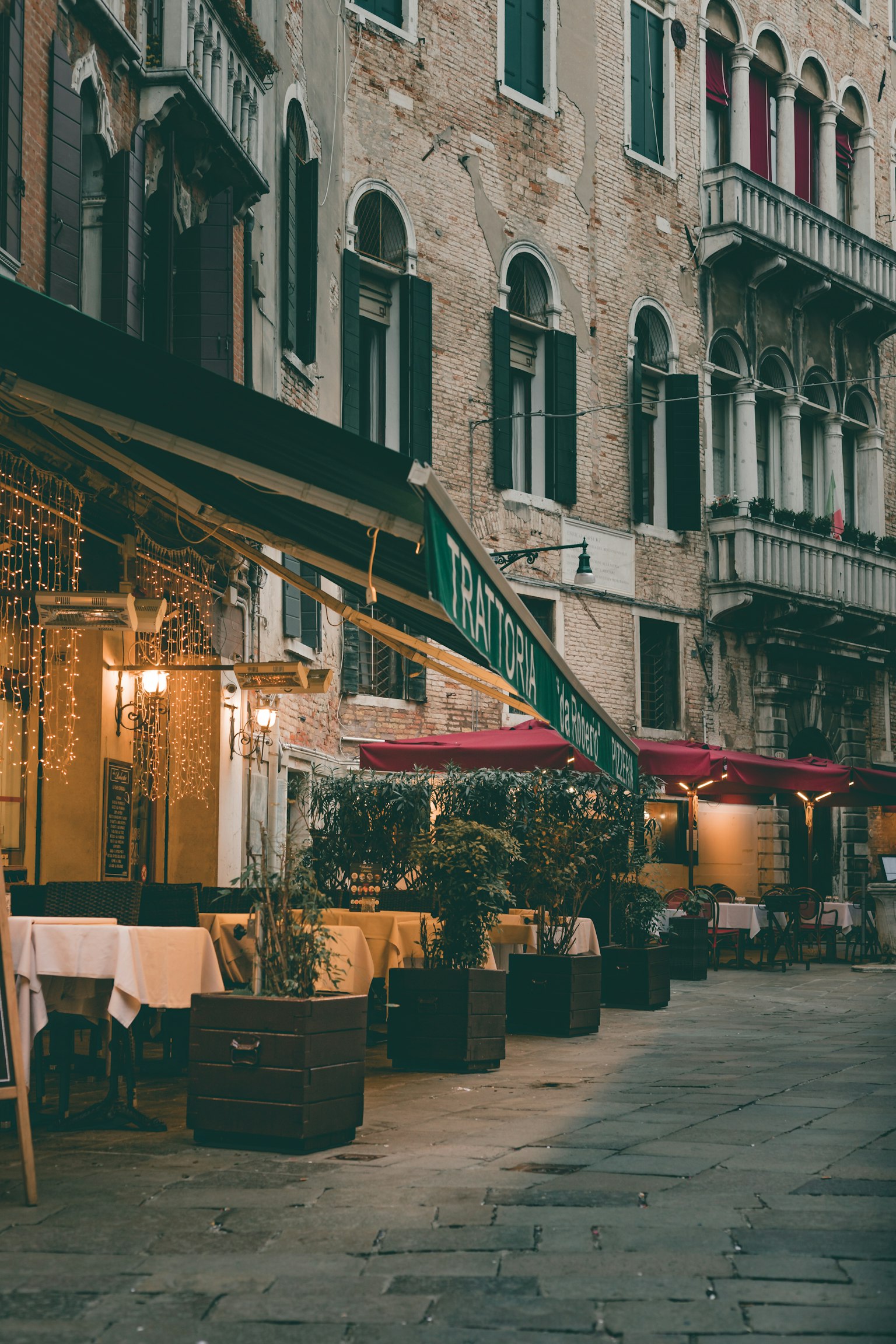 Venezianische Straße mit Restaurantterrassen und Topfpflanzen