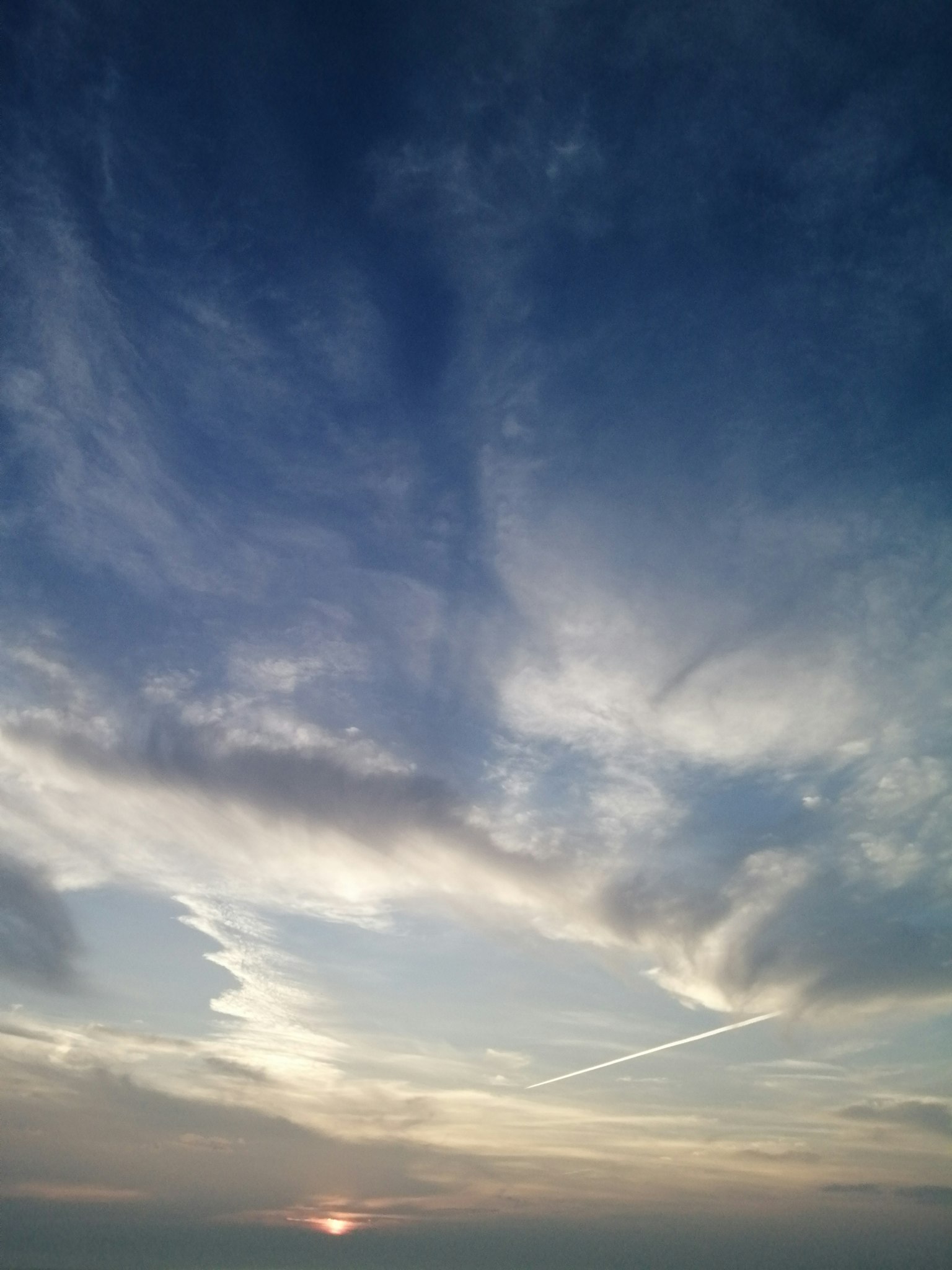 Expansive blue clouds with a sunset in the background
