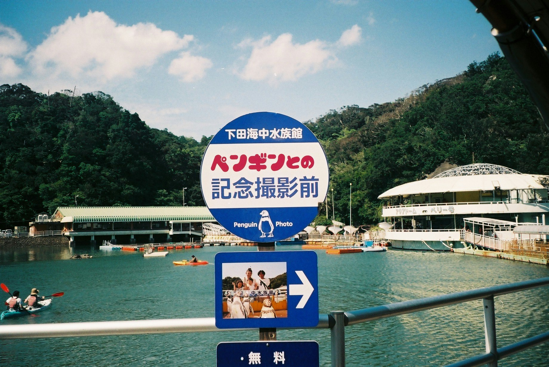 水辺の記念撮影案内看板とプール施設のある風景