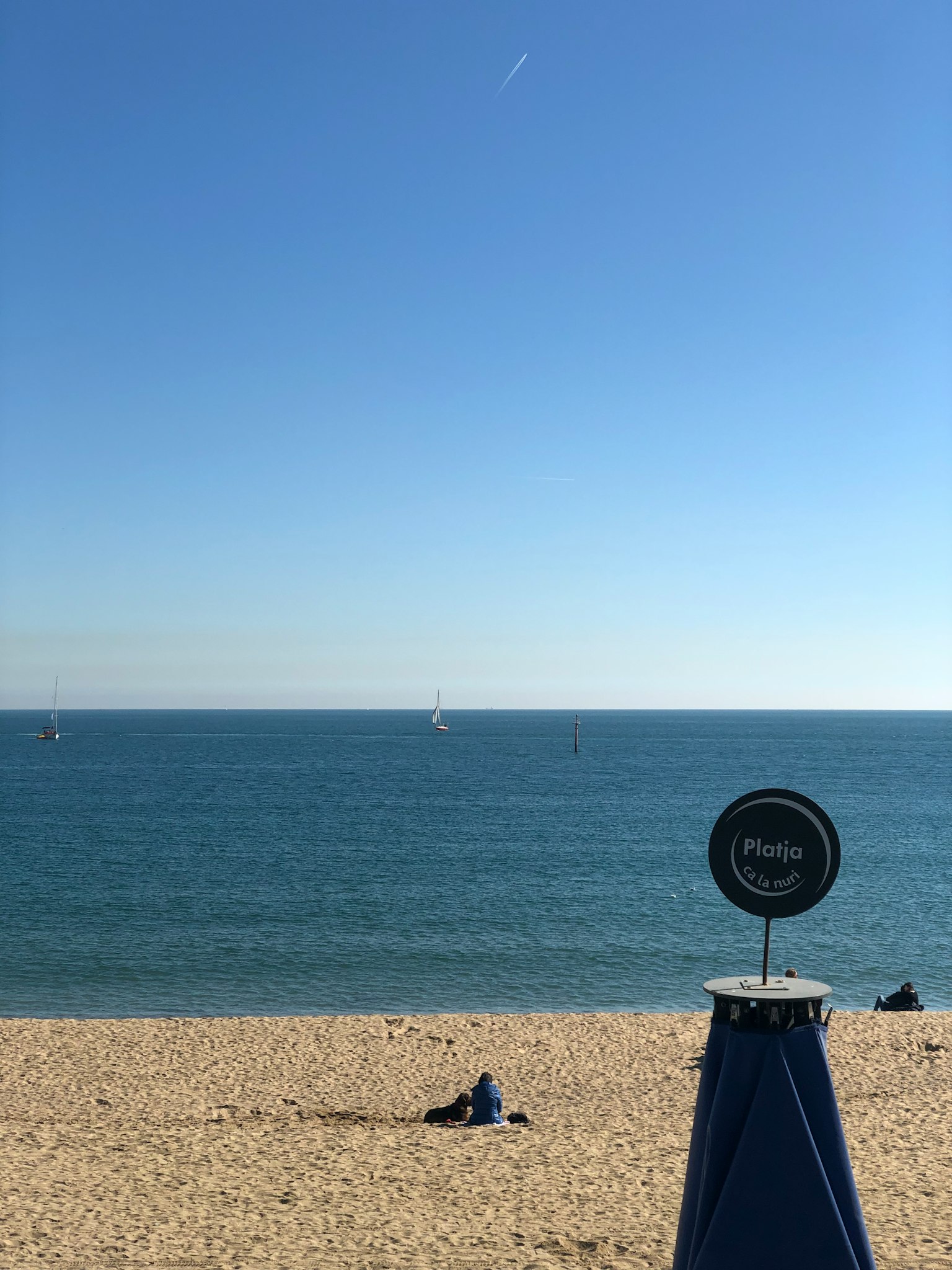 晴空下蓝色海洋的海滩景象，有一个人躺着