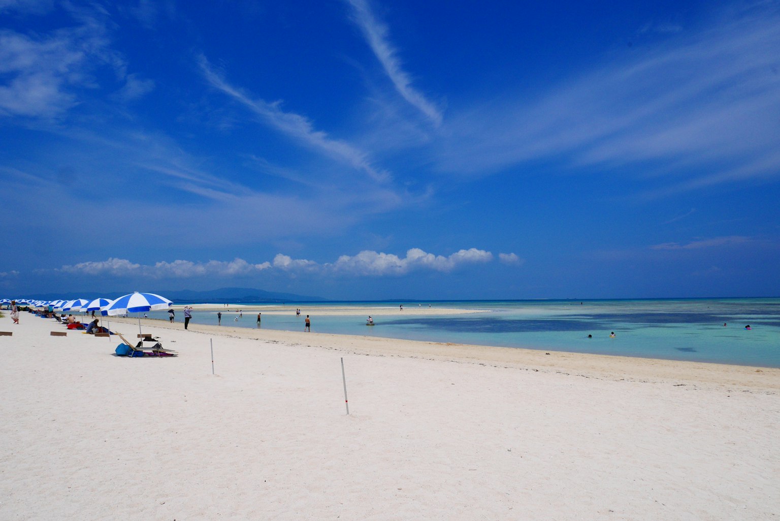Spiaggia di sabbia bianca e cielo blu con ombrelloni e persone