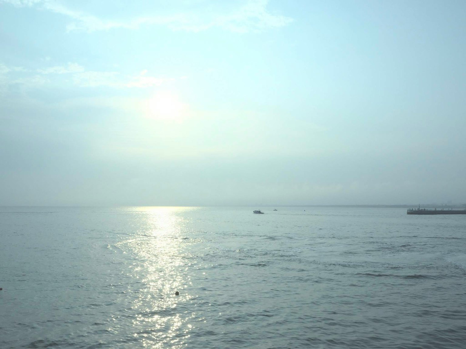 Laut tenang yang memantulkan cahaya dan awan lembut
