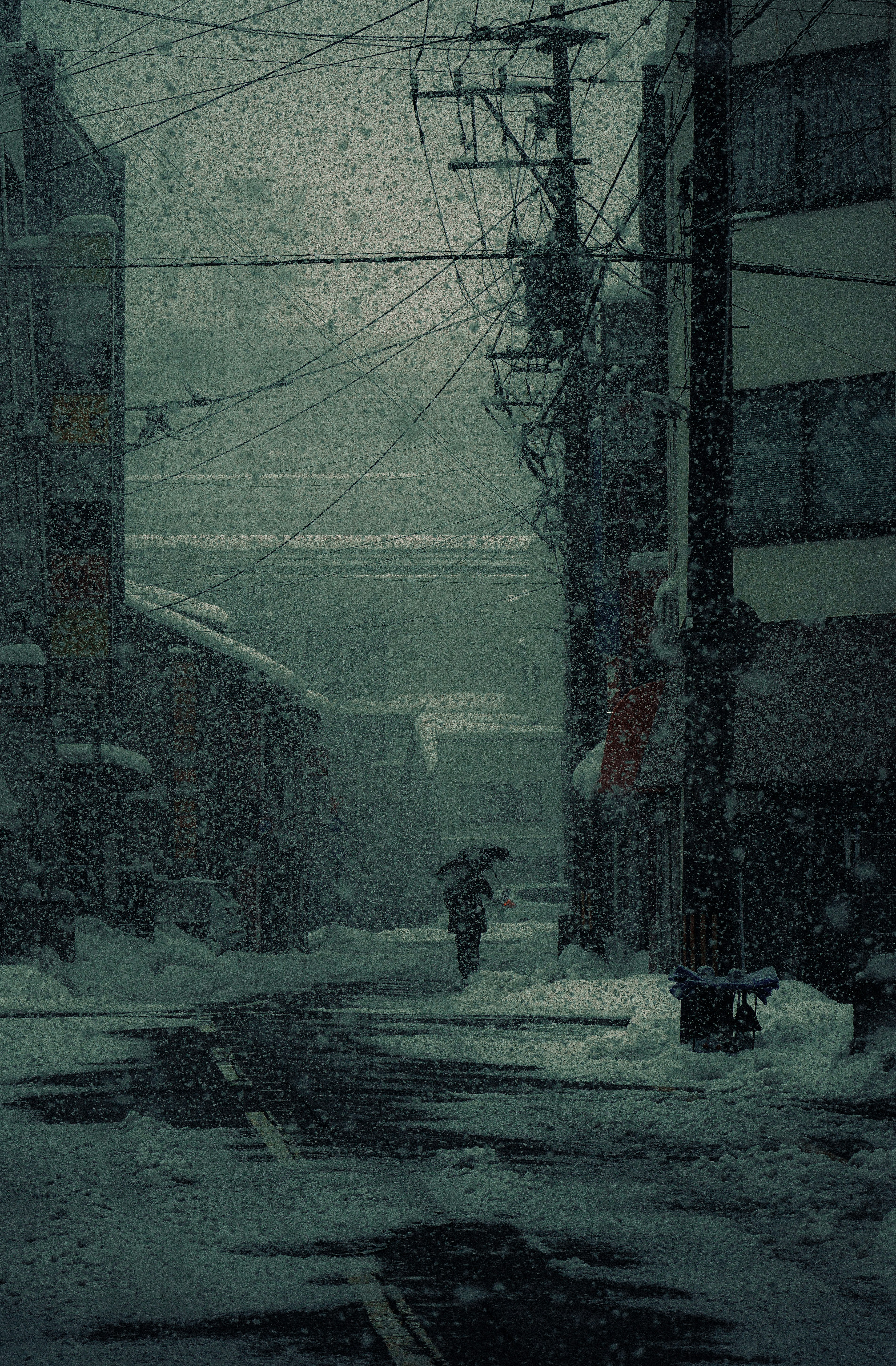 雪の降る路地の電柱と街並み
