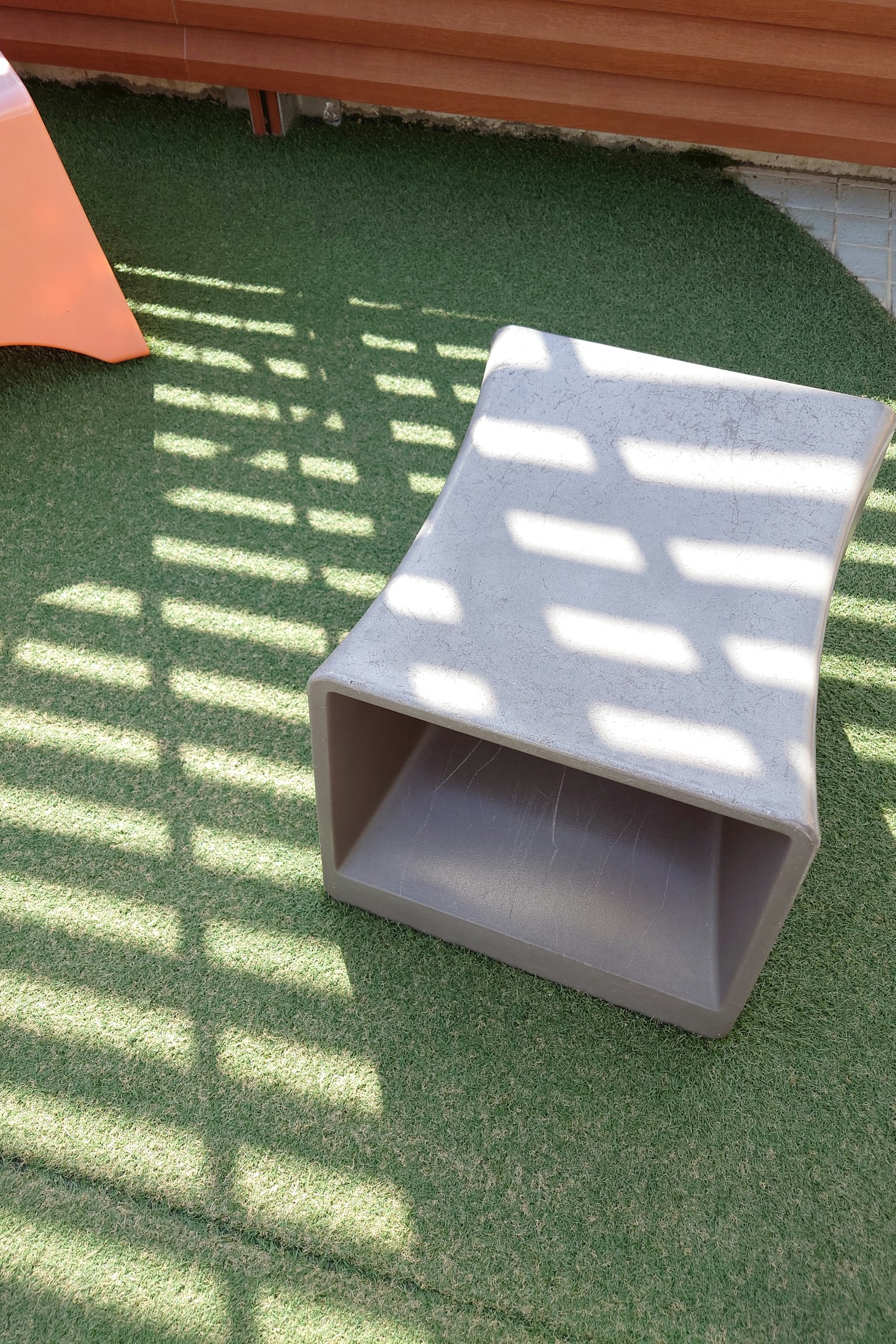 Banco de concreto al aire libre con sombras a rayas visibles