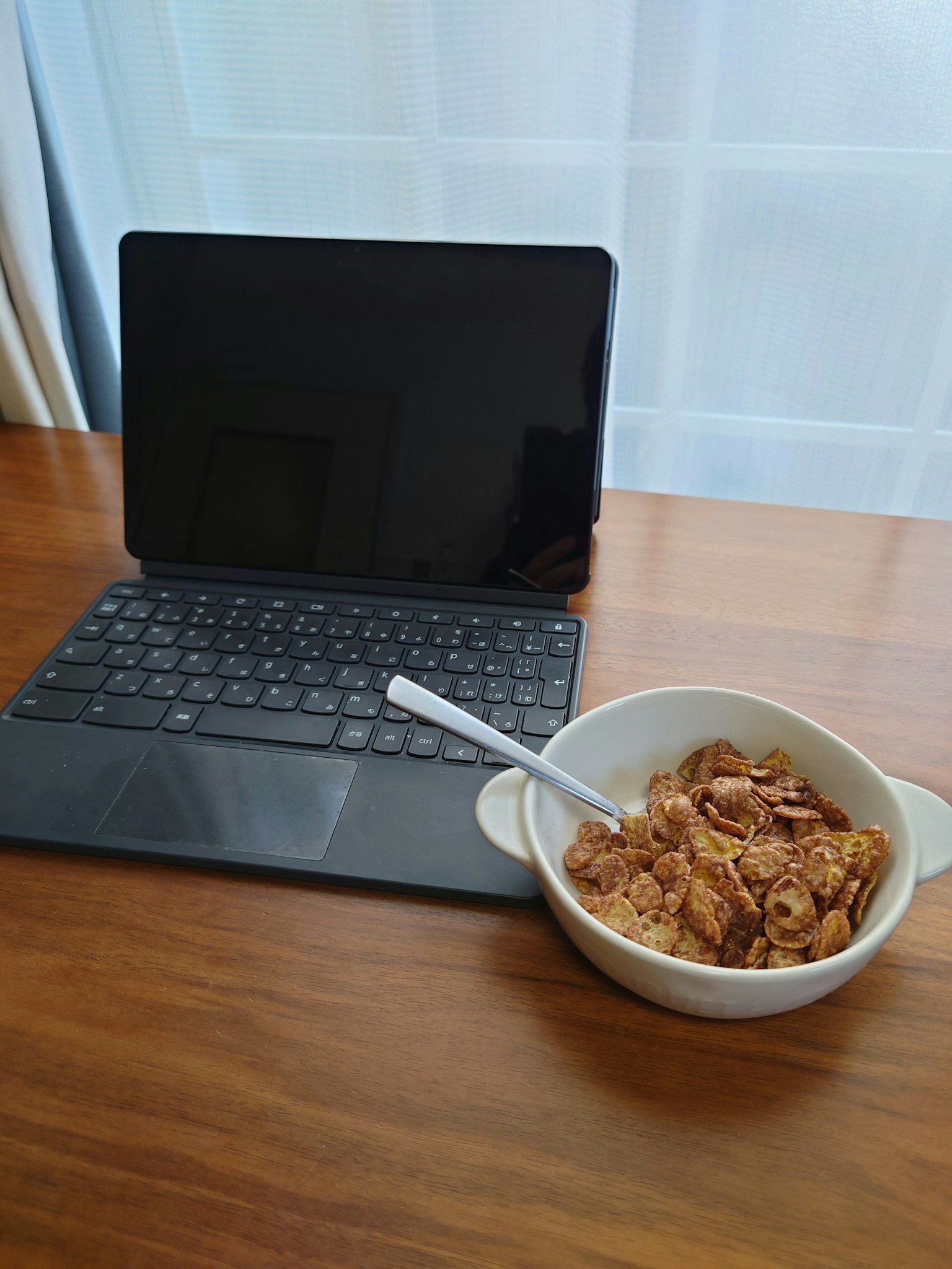 Une tablette et un bol de céréales sur une table en bois