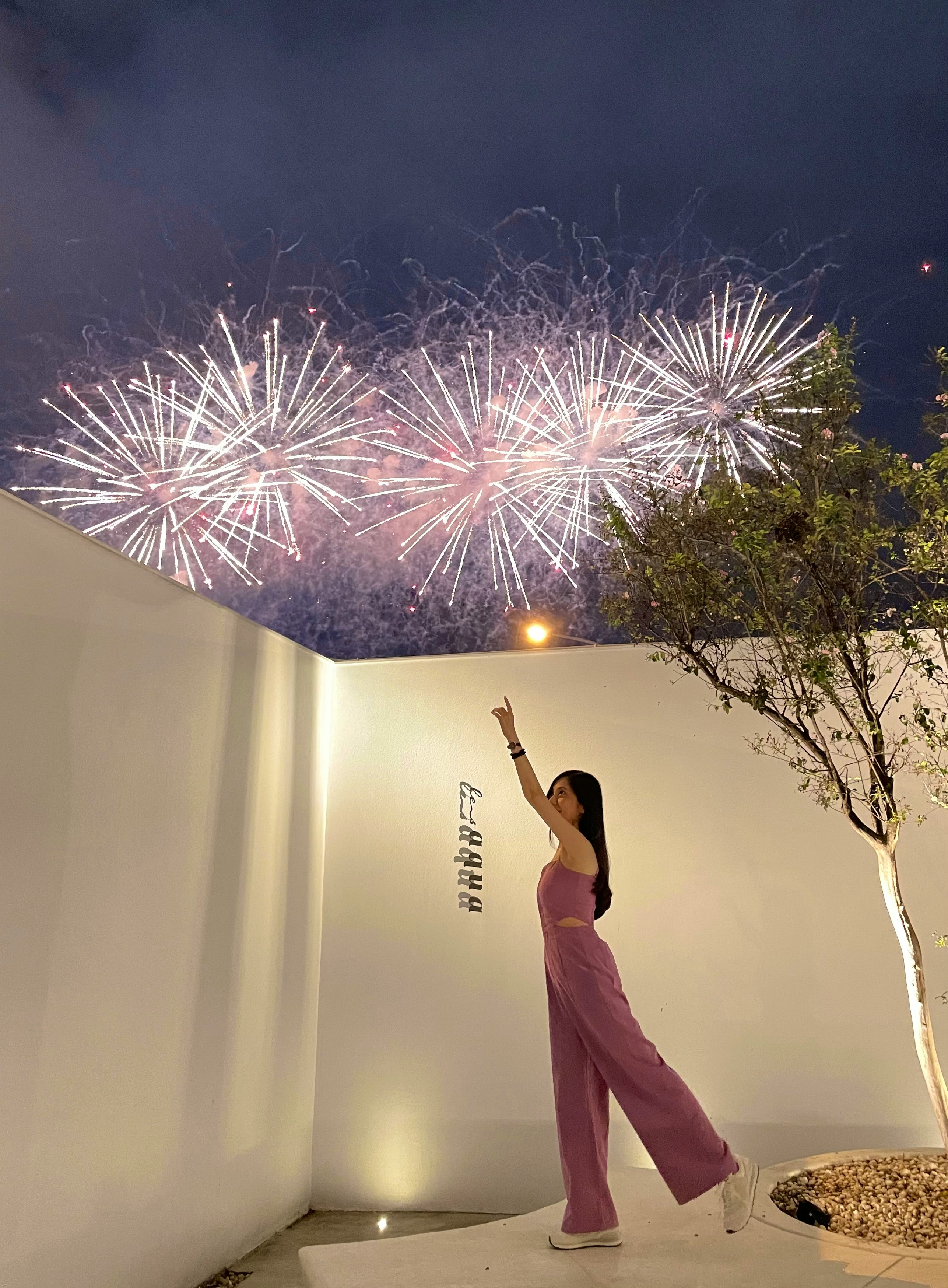 夜空に広がる花火と光を見上げる人物のシルエット
