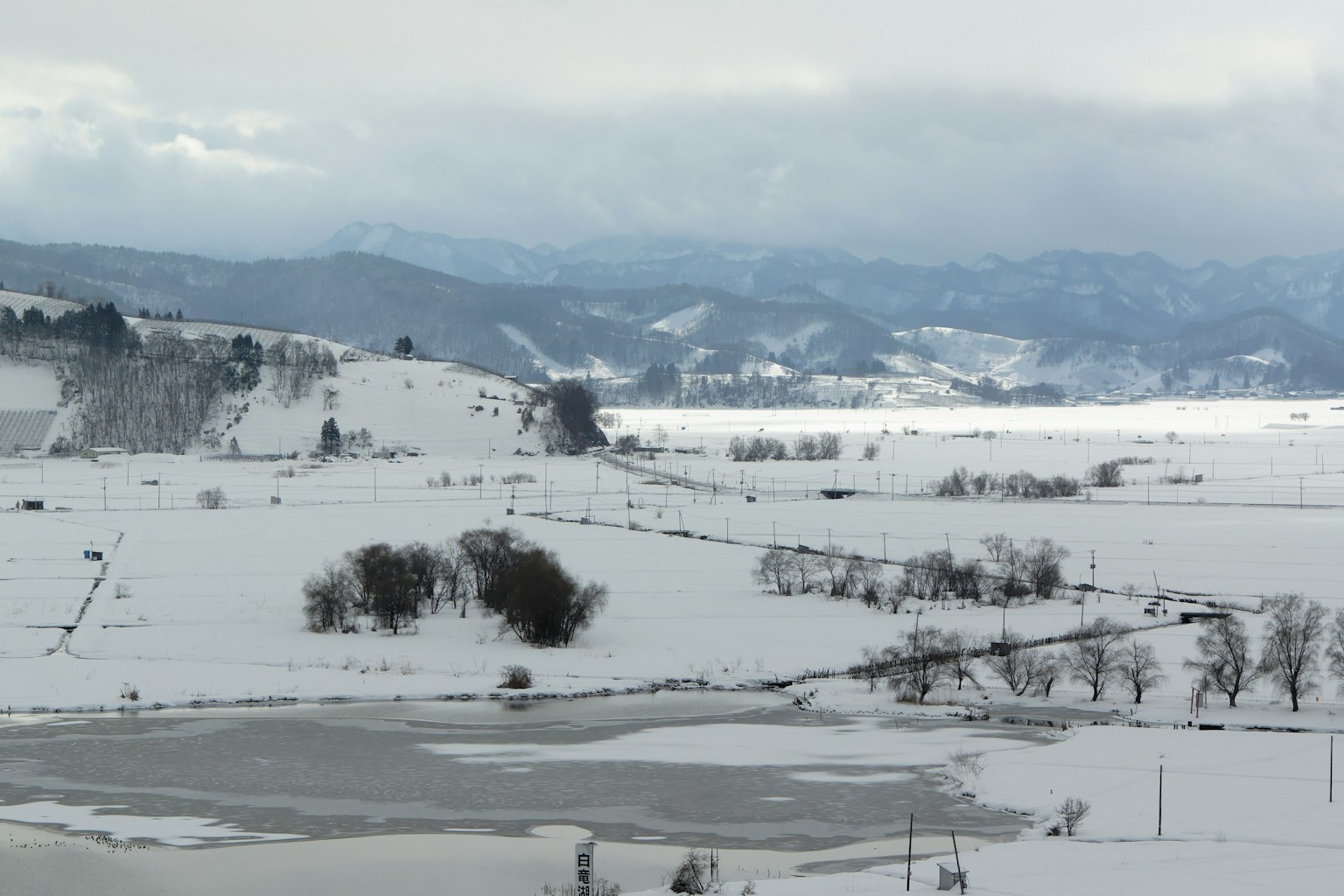 Snow-covered landscape with distant mountains visible