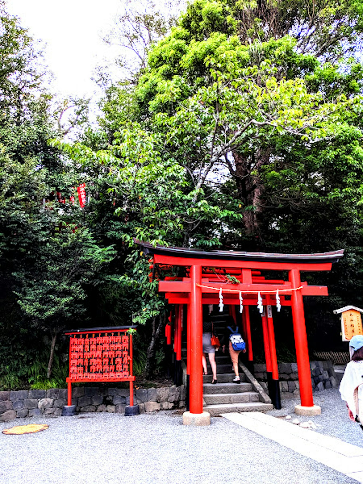 A scenic view of a shrine with a red torii gate and people approaching it