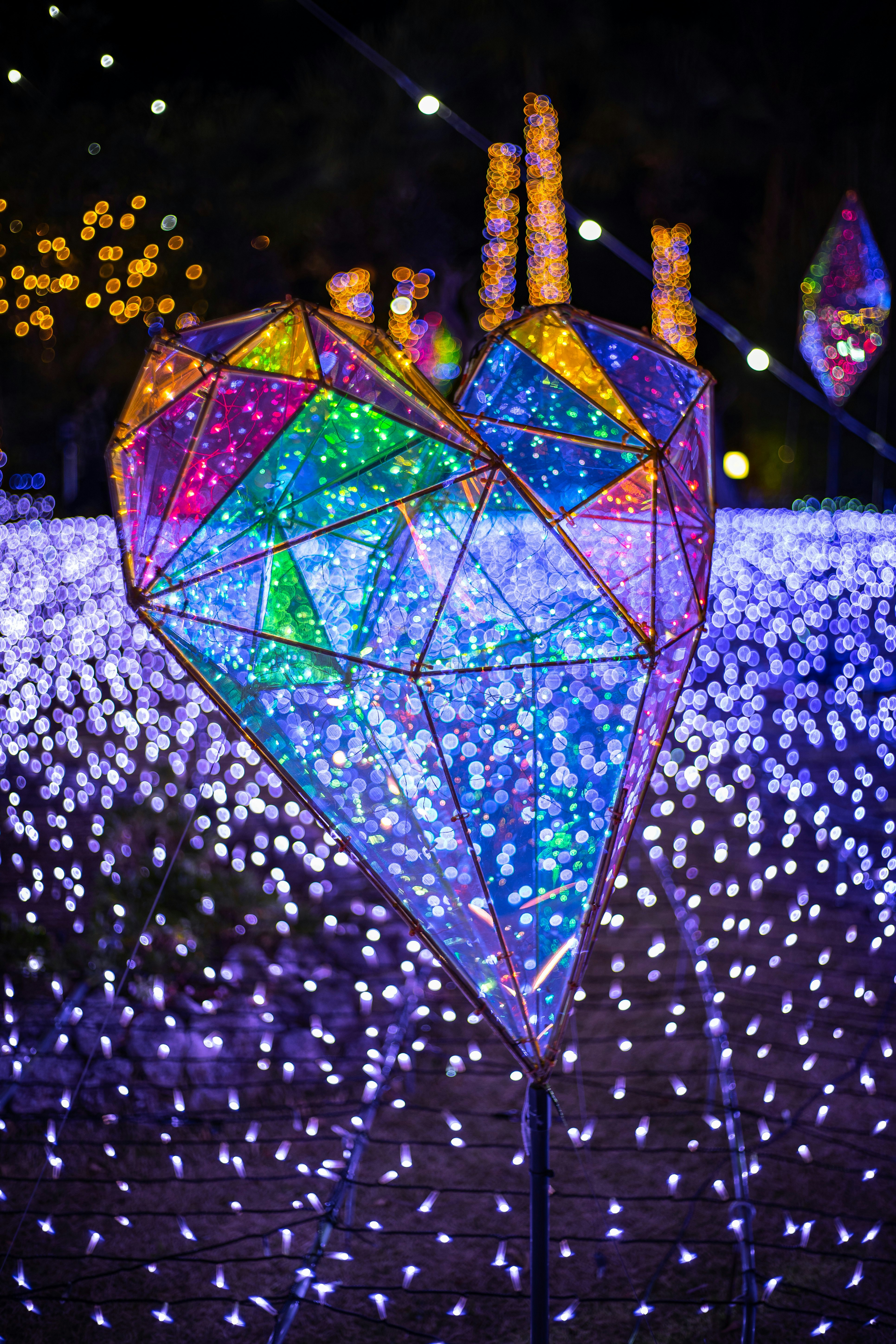 一个心形灯光雕塑在夜晚环境中散发五彩缤纷的光芒
