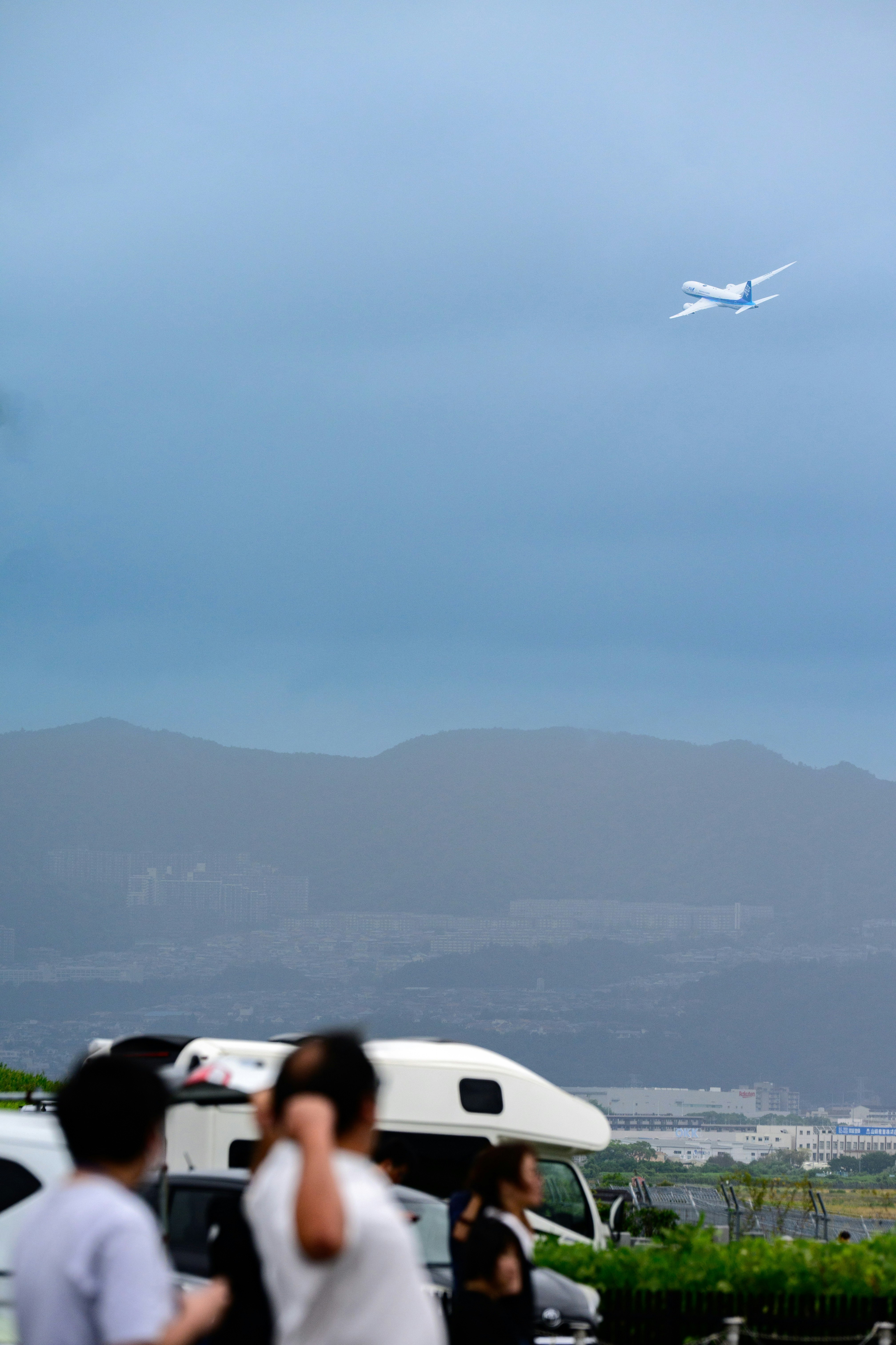 山並みを背景に飛行機が空を横切る