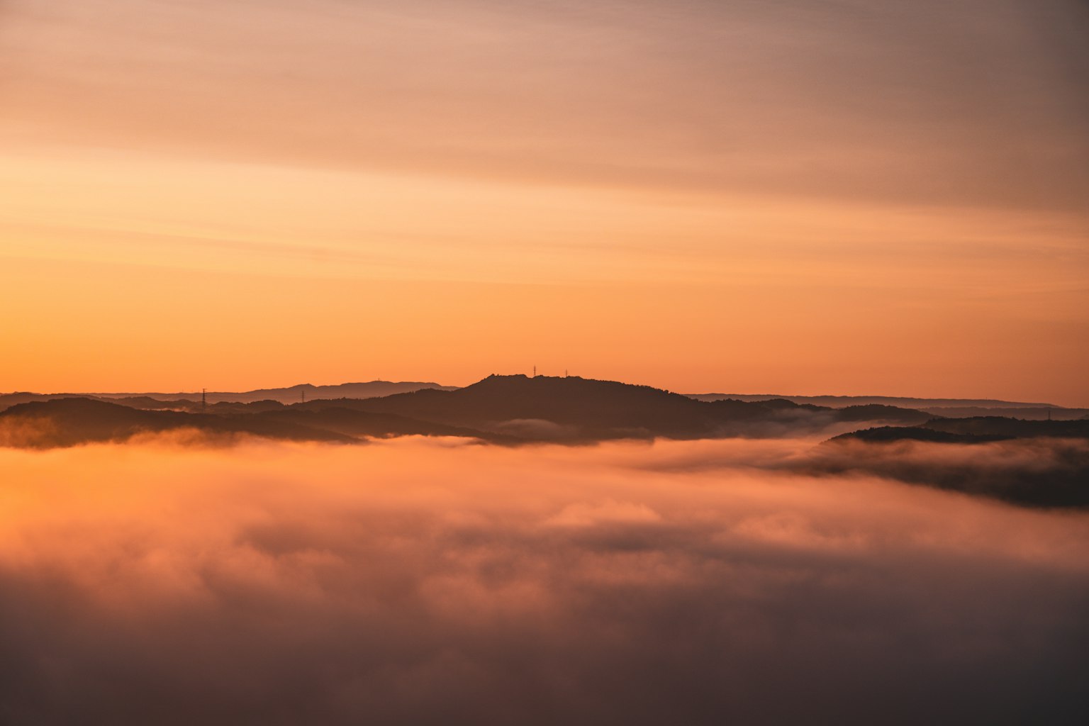 Cima de montaña sobre un mar de niebla al atardecer