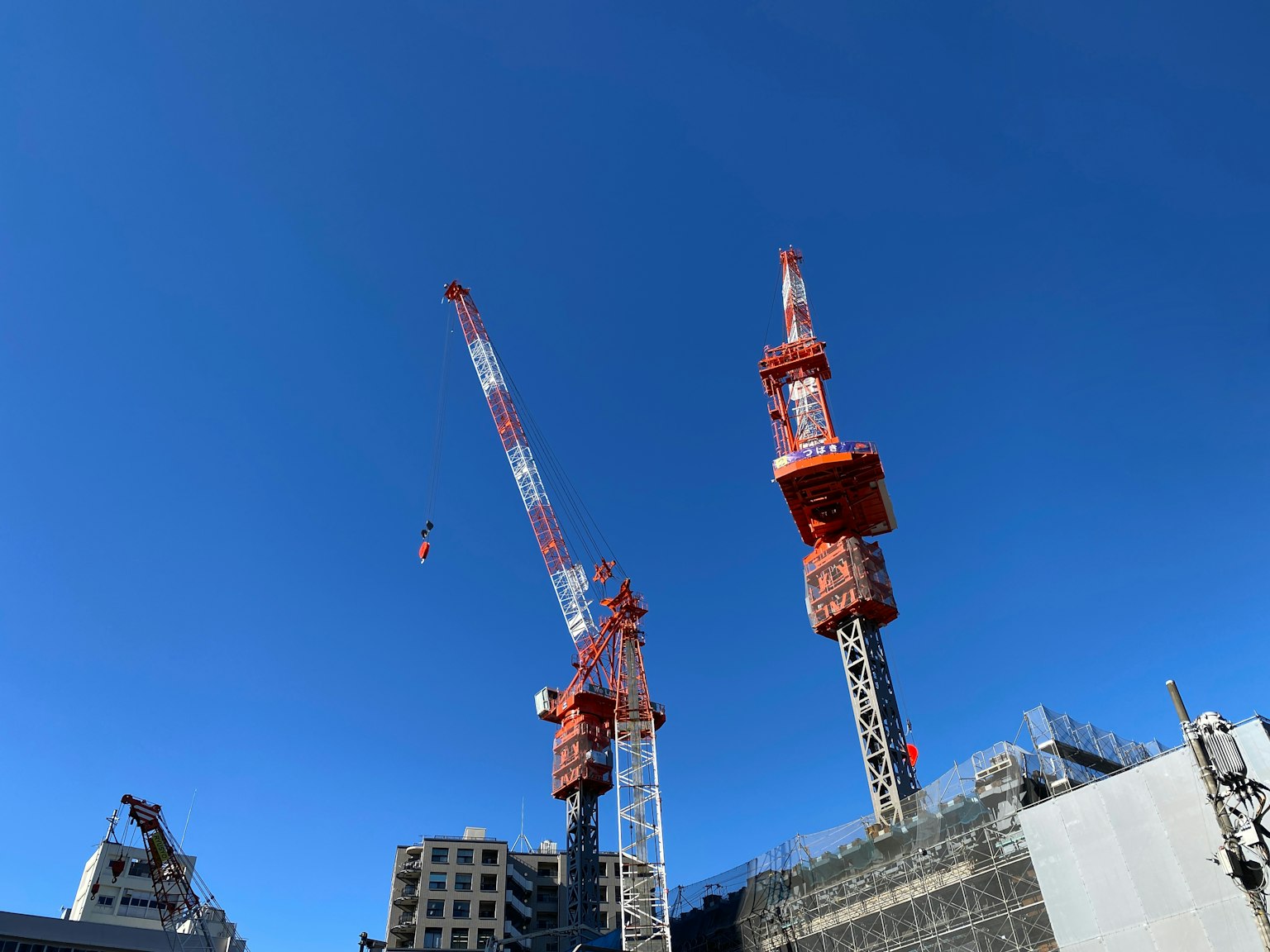 Dos grúas y un sitio de construcción bajo un cielo azul claro