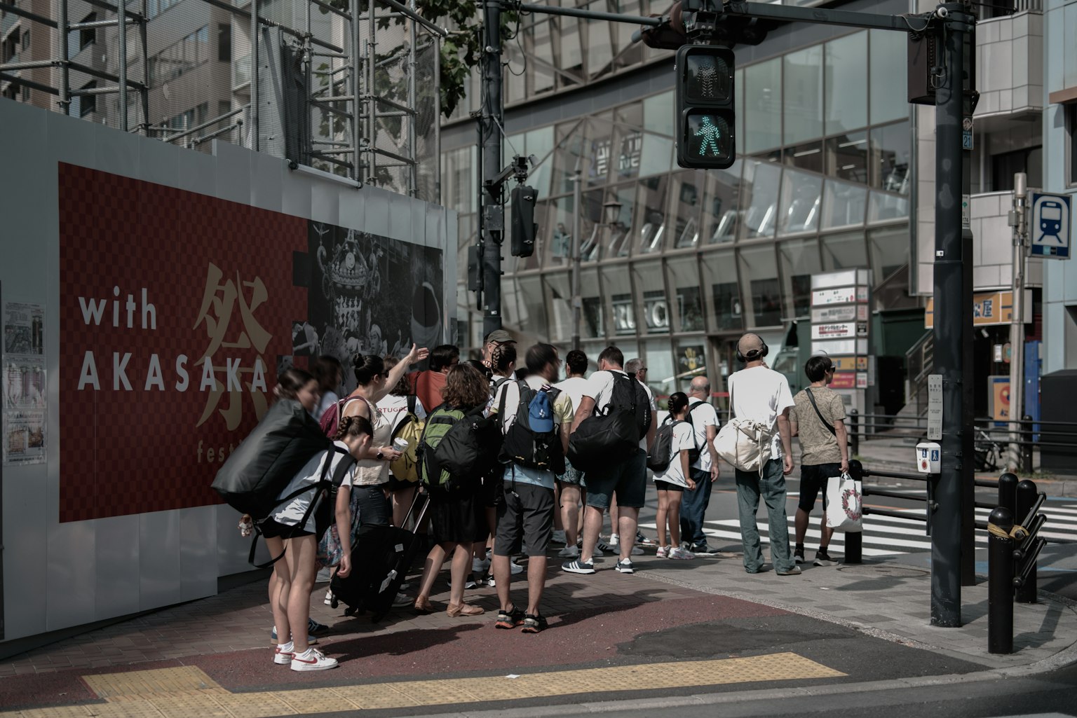 人们在斑马线上等待,背景有红色标志和现代建筑