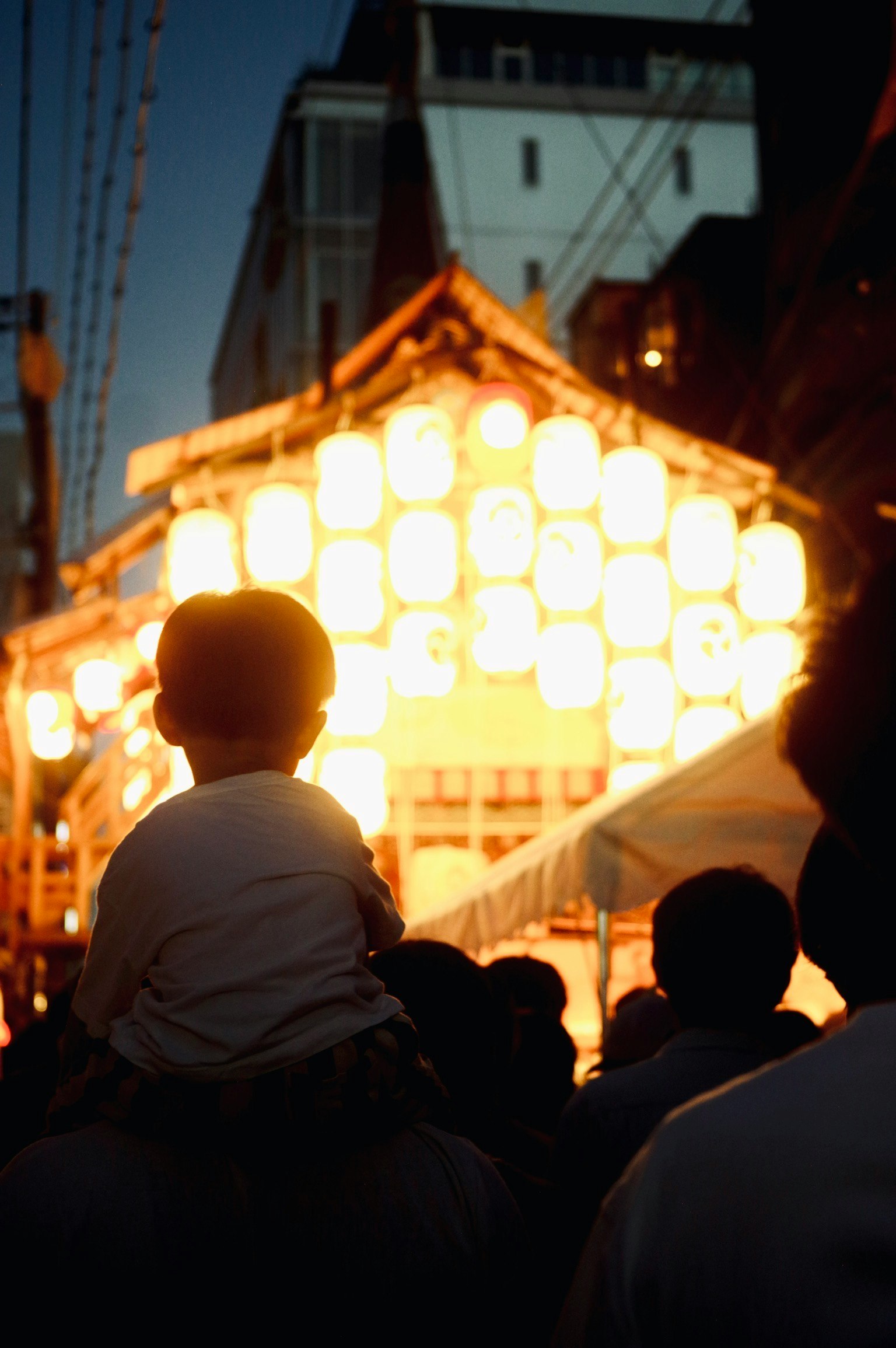 Silhouette di un genitore che porta un bambino durante un festival con lanterne illuminate di notte