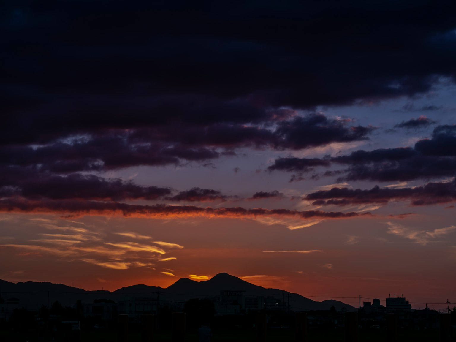 Silhouette di montagne e nuvole con un tramonto vibrante
