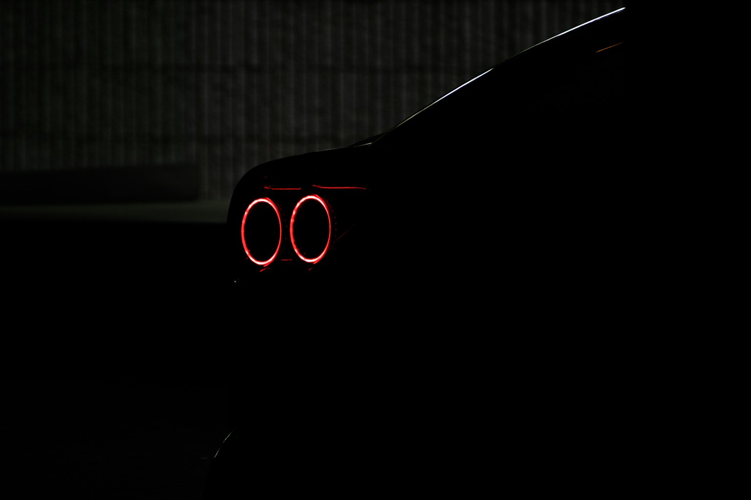 어둠 속에서 빛나는 테일 라이트가 있는 자동차의 실루엣