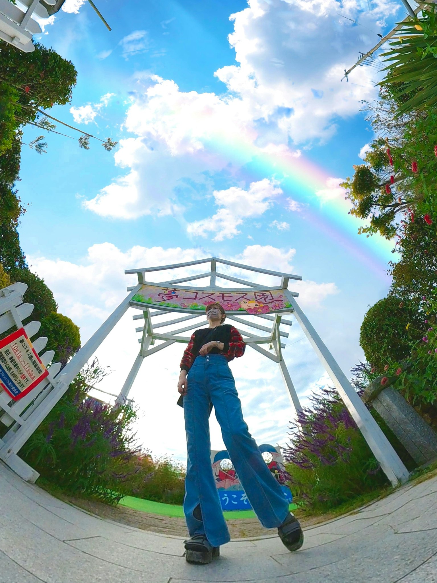 Person steht unter einem Regenbogen mit einem weißen Bogen