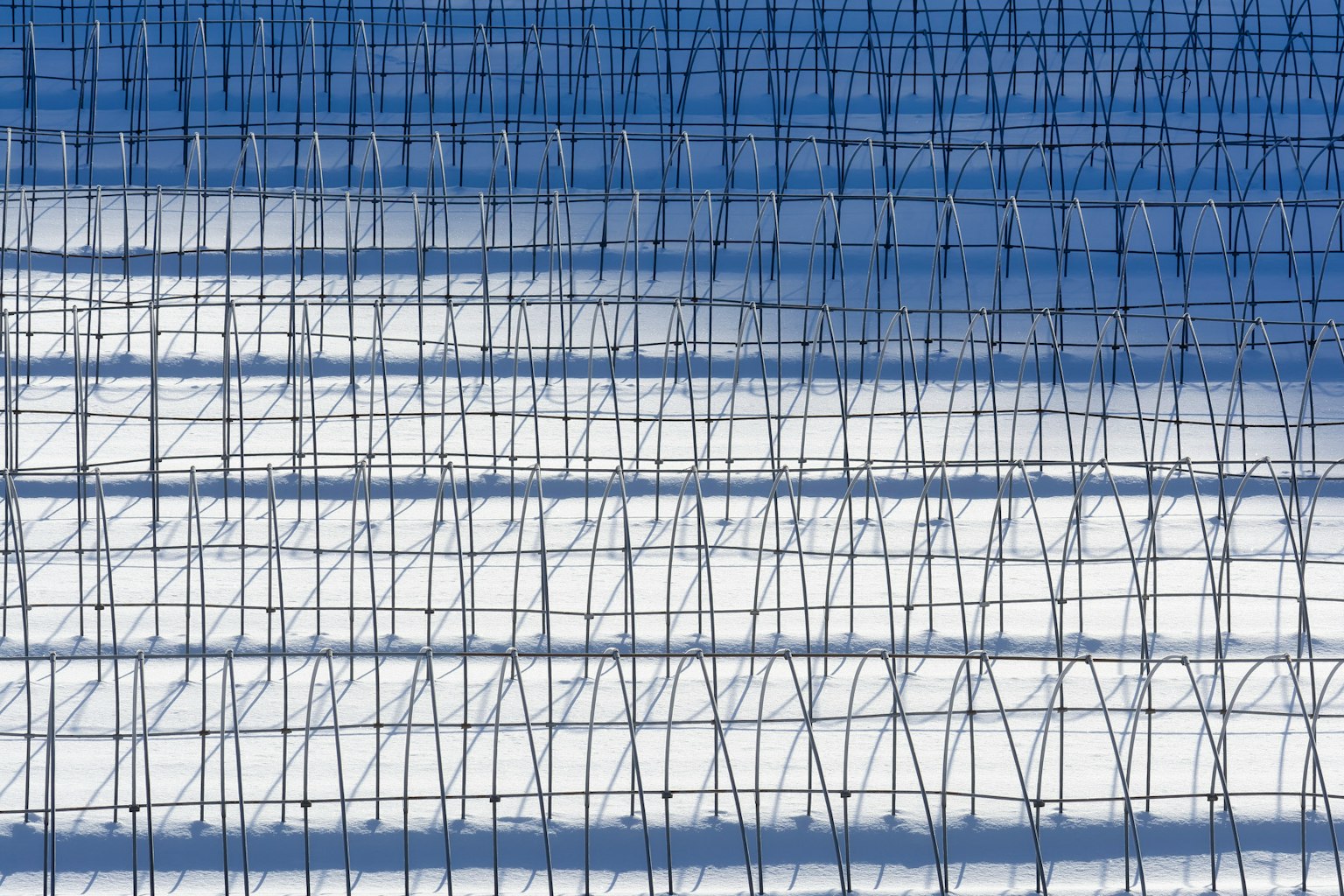 Structure en grille projetant des ombres sur une surface enneigée