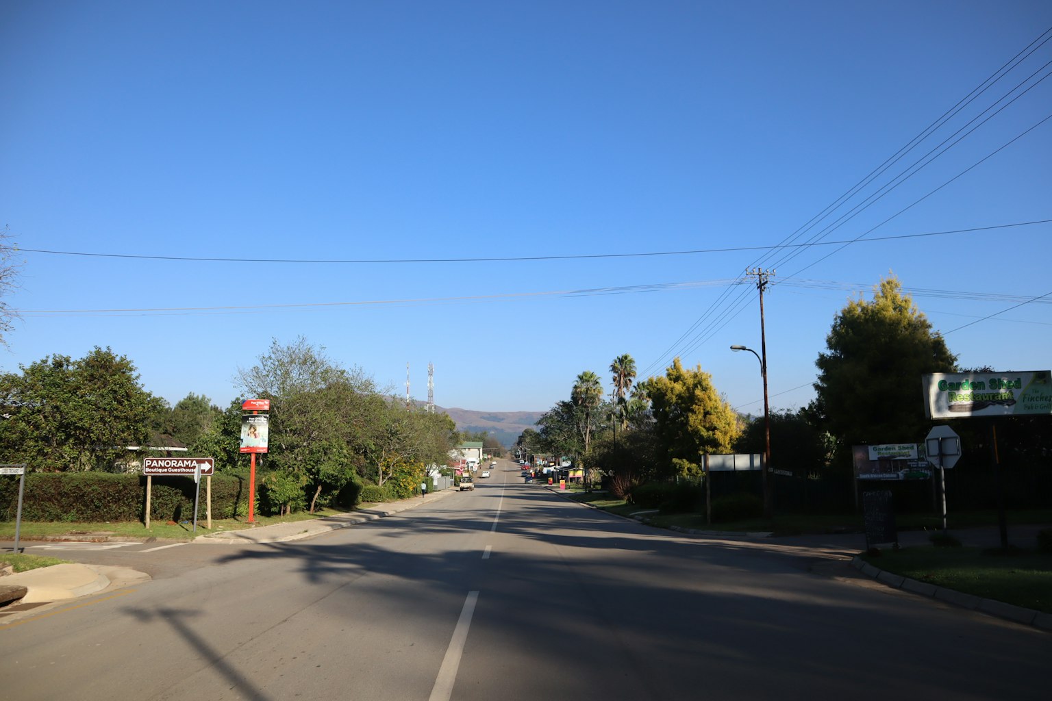 藍天之下寧靜的街道場景有公車站和綠色樹木