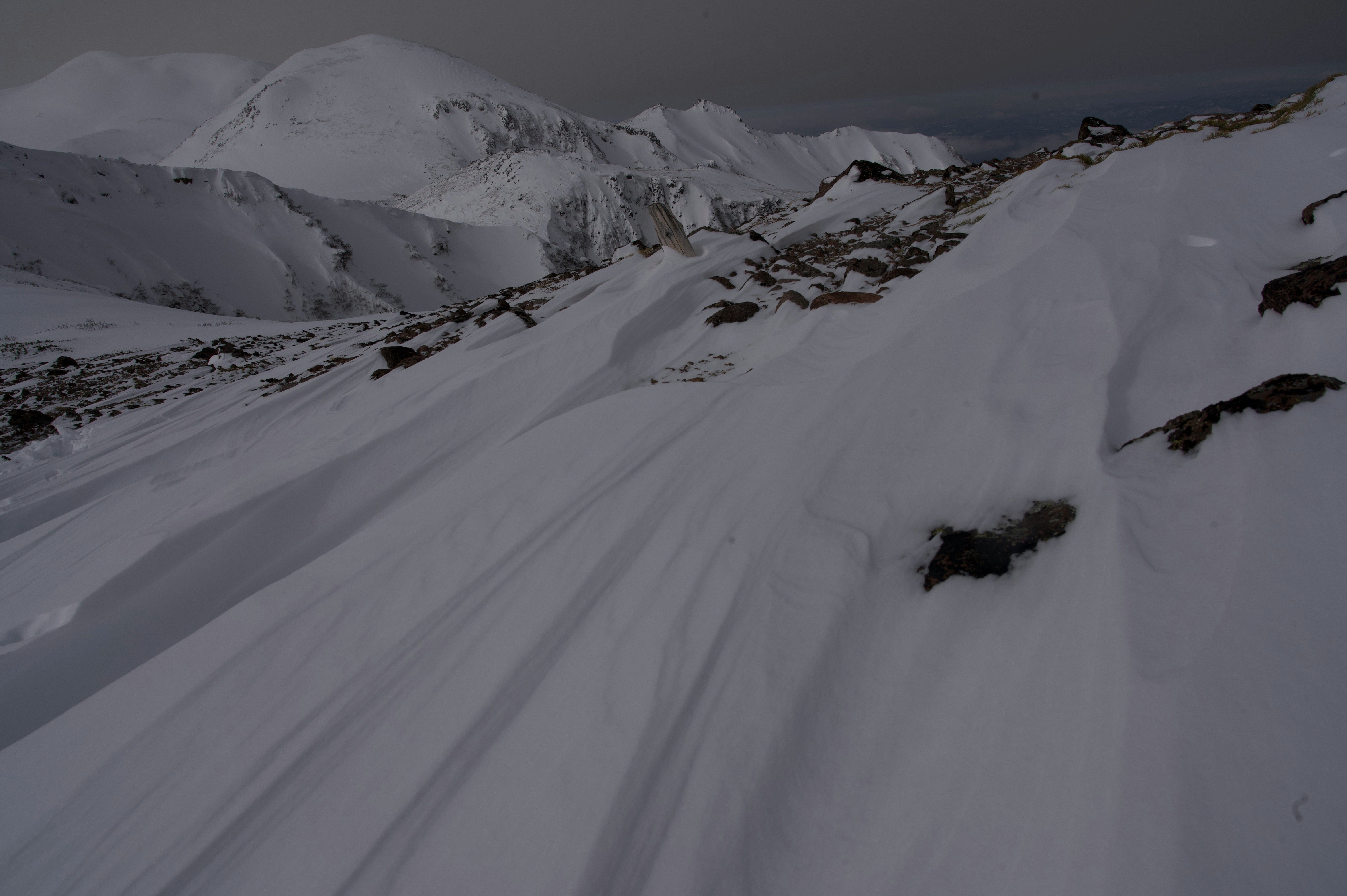 雪の斜面を走るスキーコースのある山岳風景