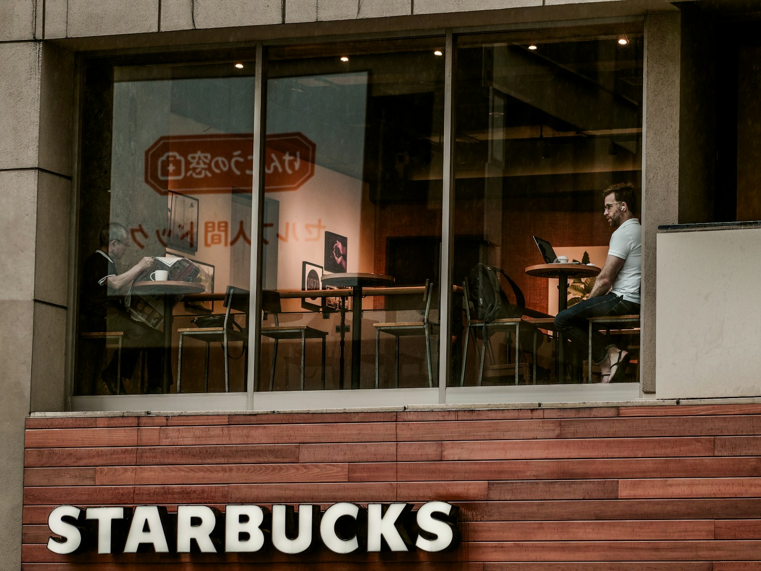 Blick aus dem Fenster von Starbucks auf das Café-Innenleben und einen Kunden