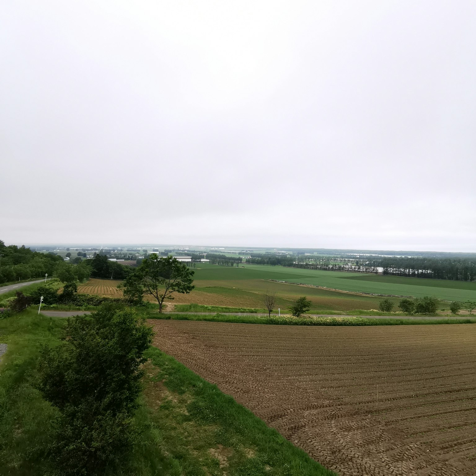 Expansive farmland under a cloudy sky with distant scenery