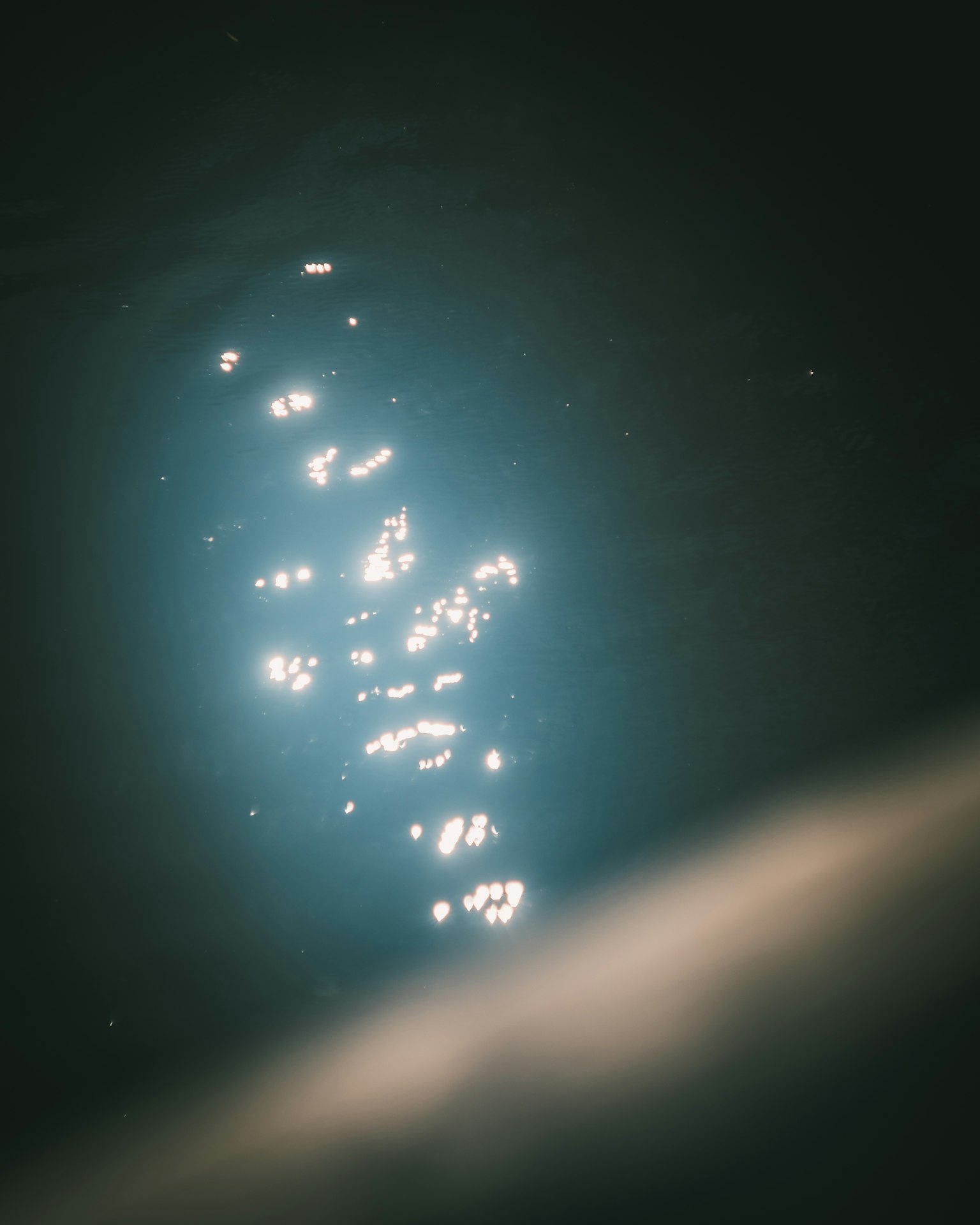 Immagine di riflessi luminosi che brillano sull'acqua con uno sfondo scuro