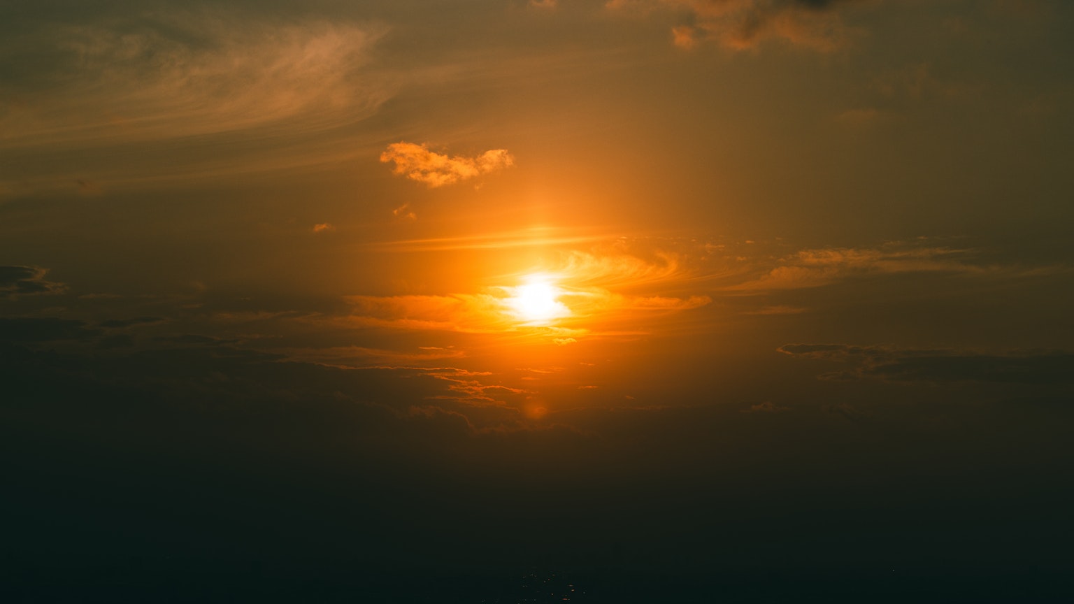 Soleil orange se couchant dans un ciel nuageux