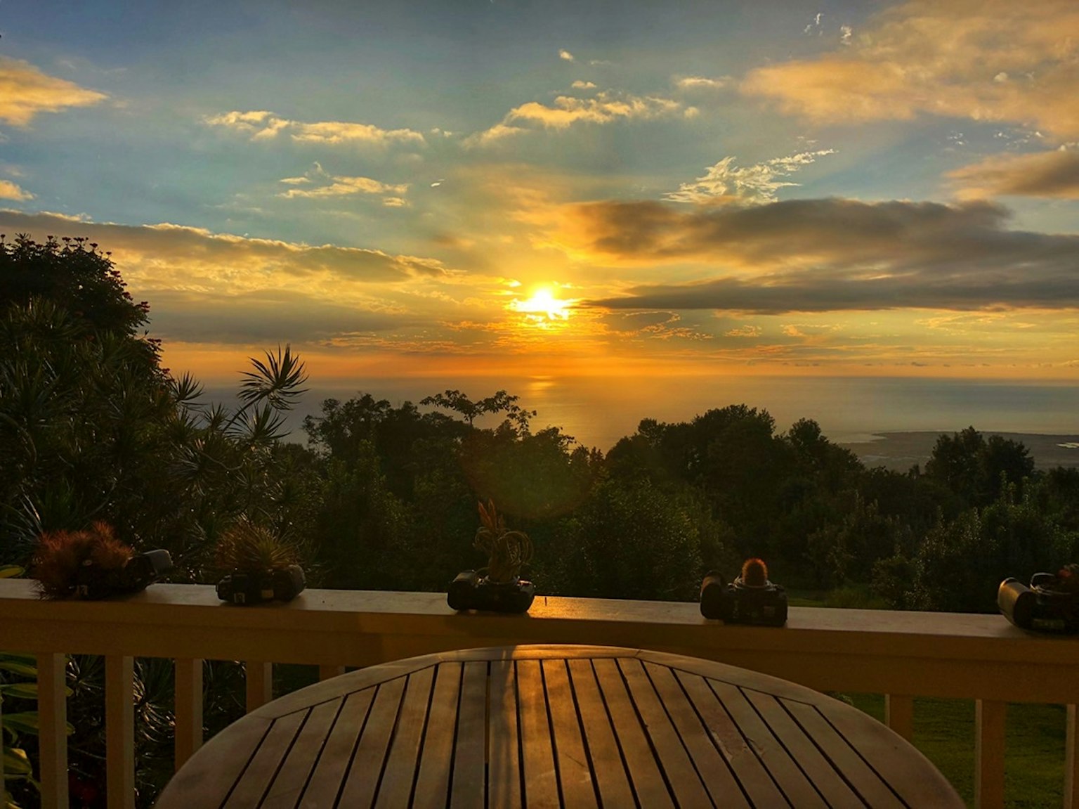Vista panoramica di un tramonto da un balcone con un tavolo di legno e piante