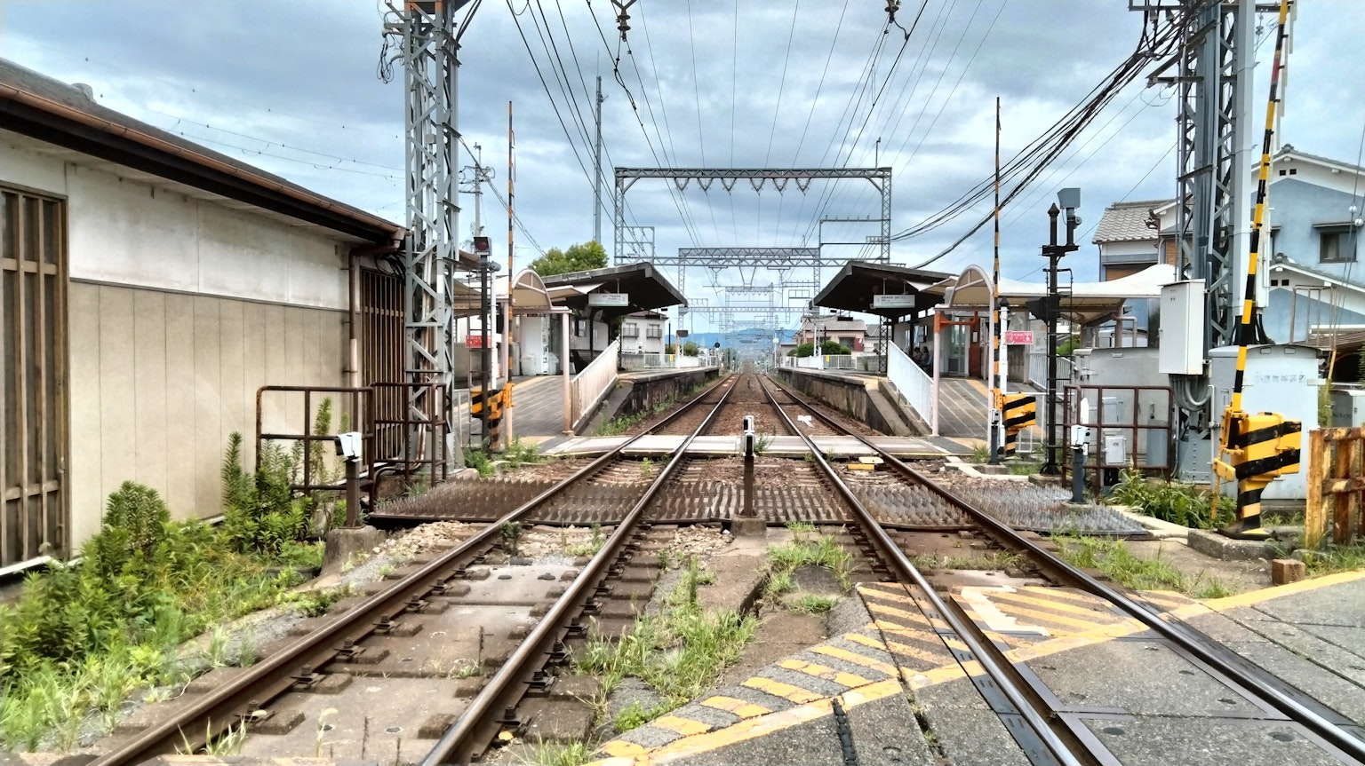 ทิวทัศน์ของสถานีรถไฟที่มีรางรถไฟและอาคารสถานีพร้อมสัญญาณรถไฟและเสา