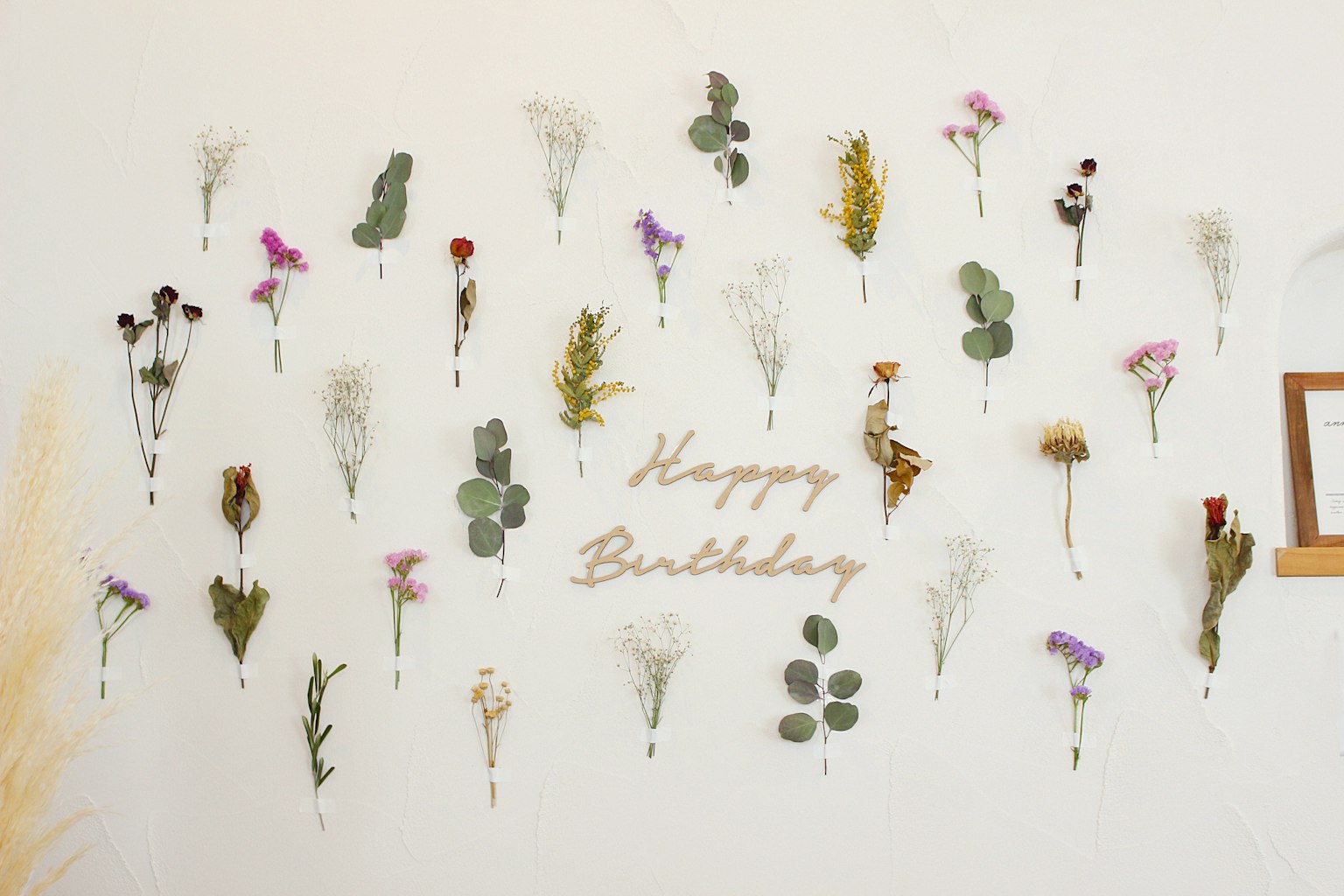 건조된 꽃과 '생일 축하합니다'라는 글자가 장식된 벽