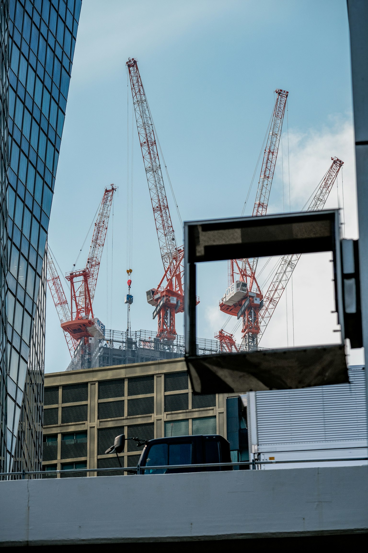 Grúas rojas visibles entre edificios contra un cielo azul