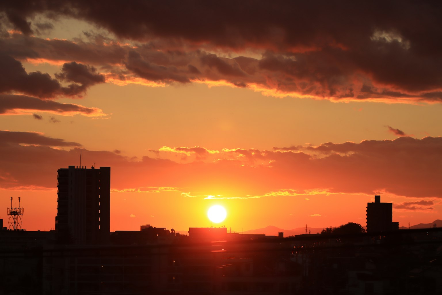 Coucher de soleil sur un horizon urbain avec silhouettes de bâtiments et couleurs vives du ciel