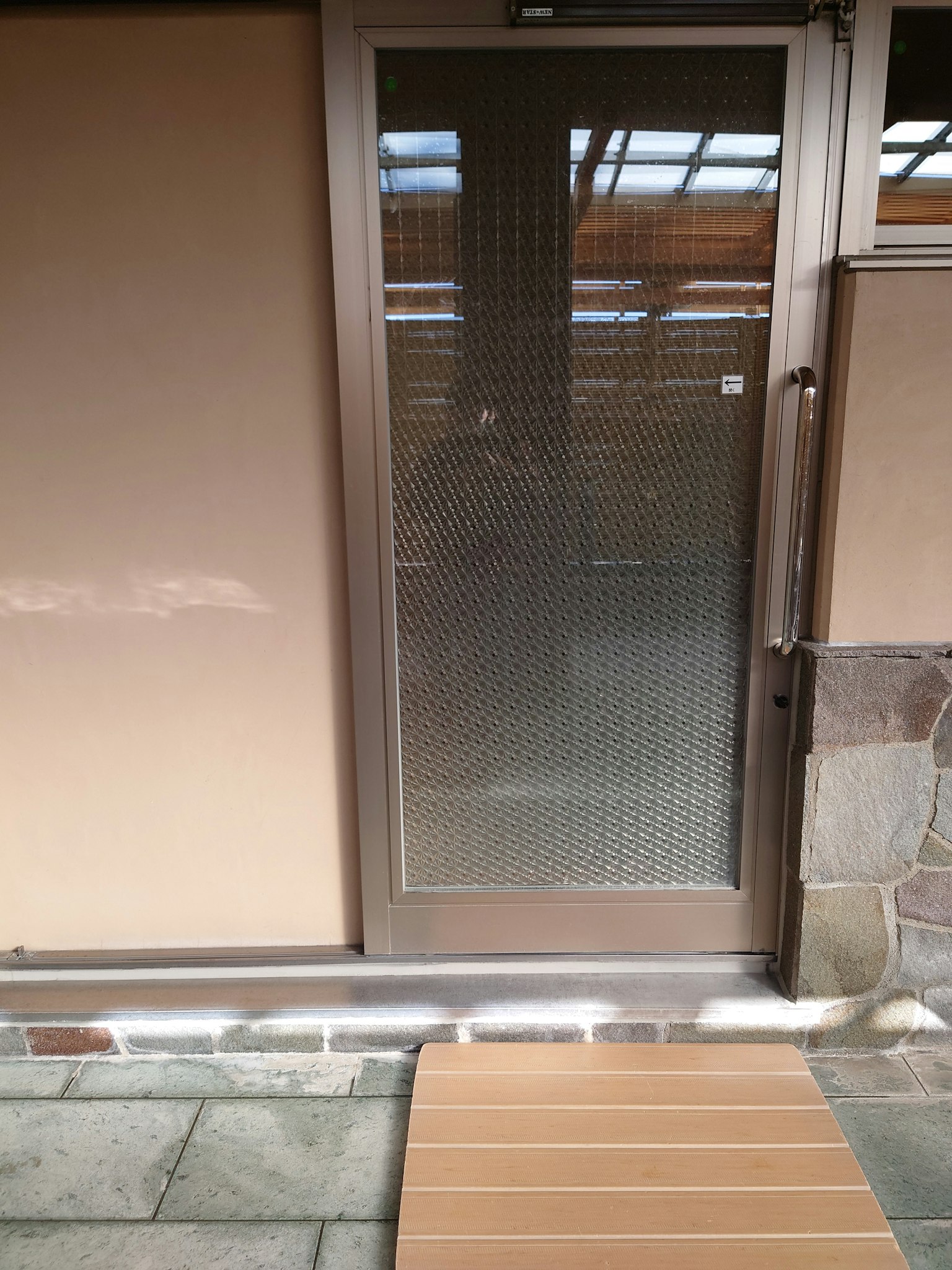 Metal-framed glass door featuring a patterned design with stone flooring