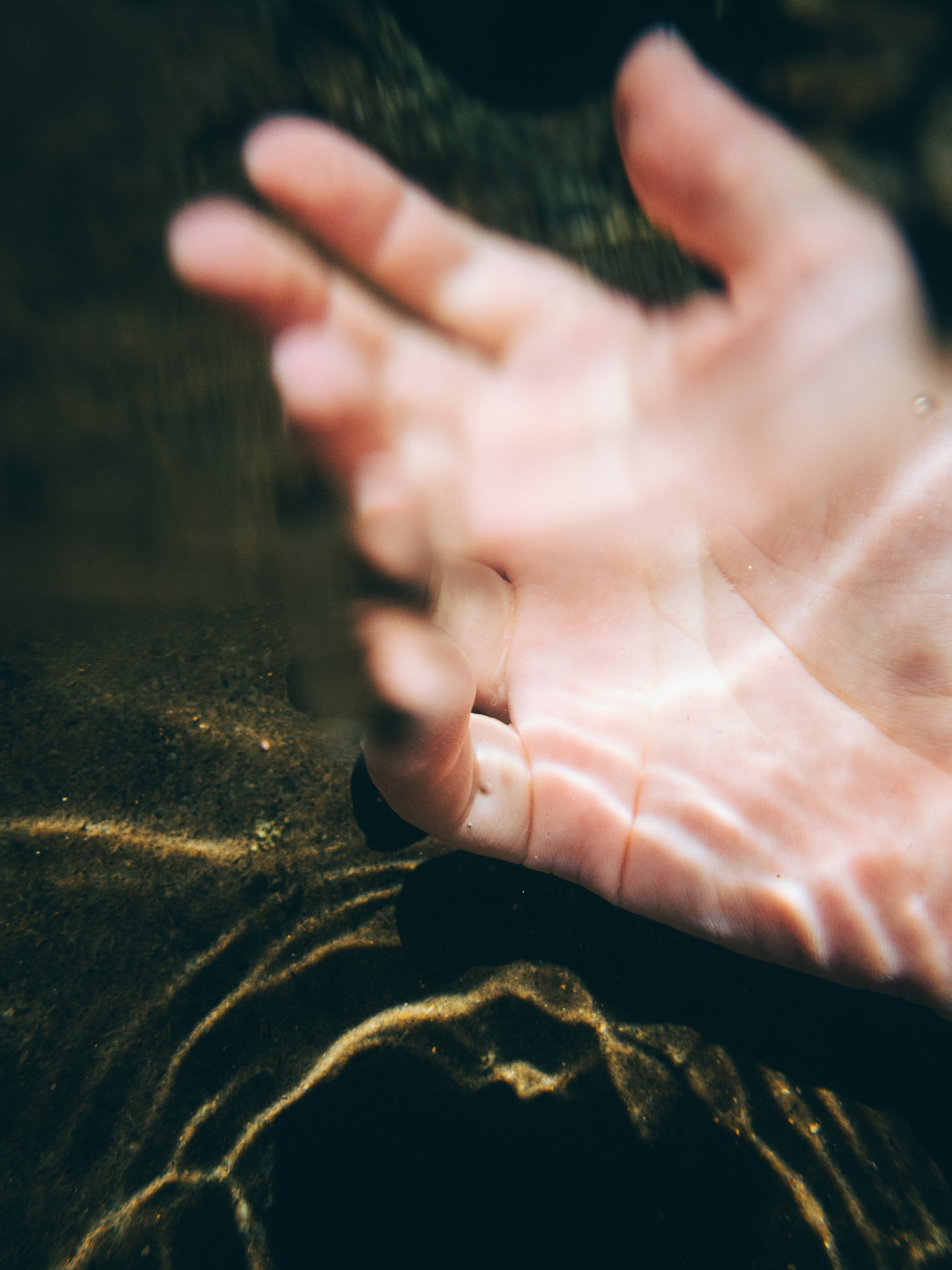 Eine Hand, die sich ausstreckt, um die Wasseroberfläche zu berühren