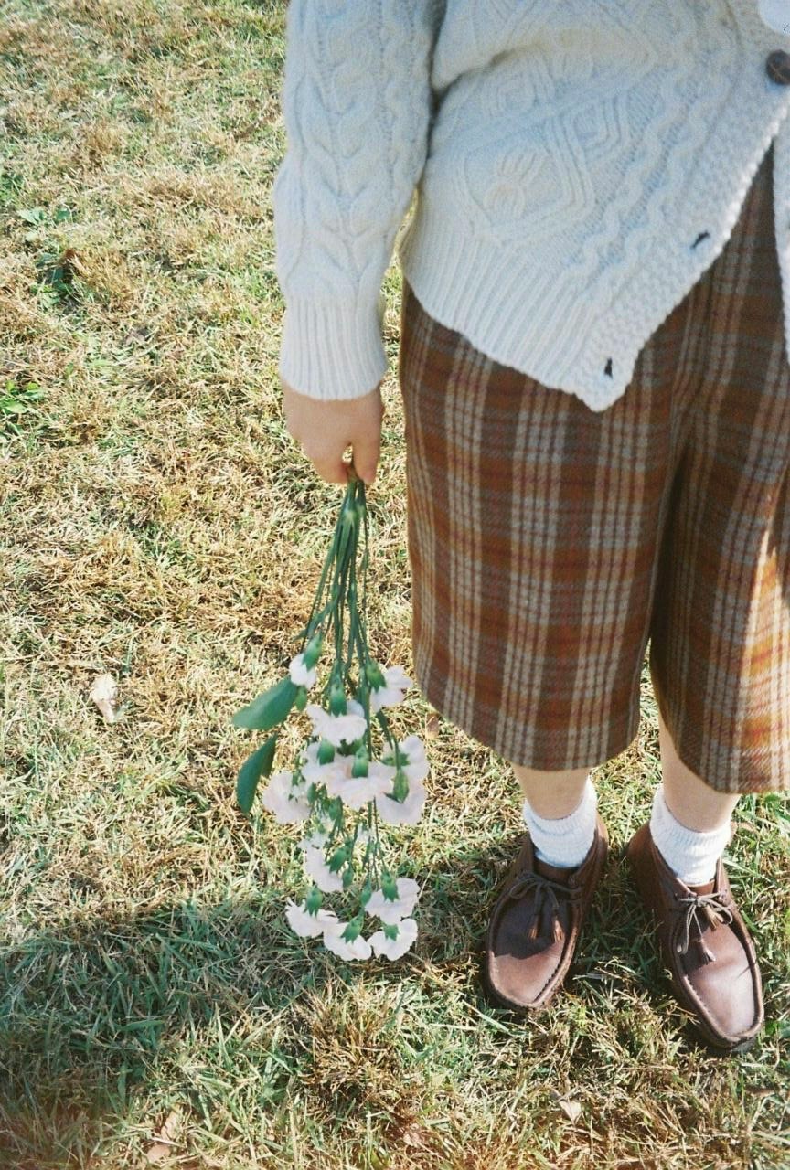 草地上手捧小花束的手部与鞋袜