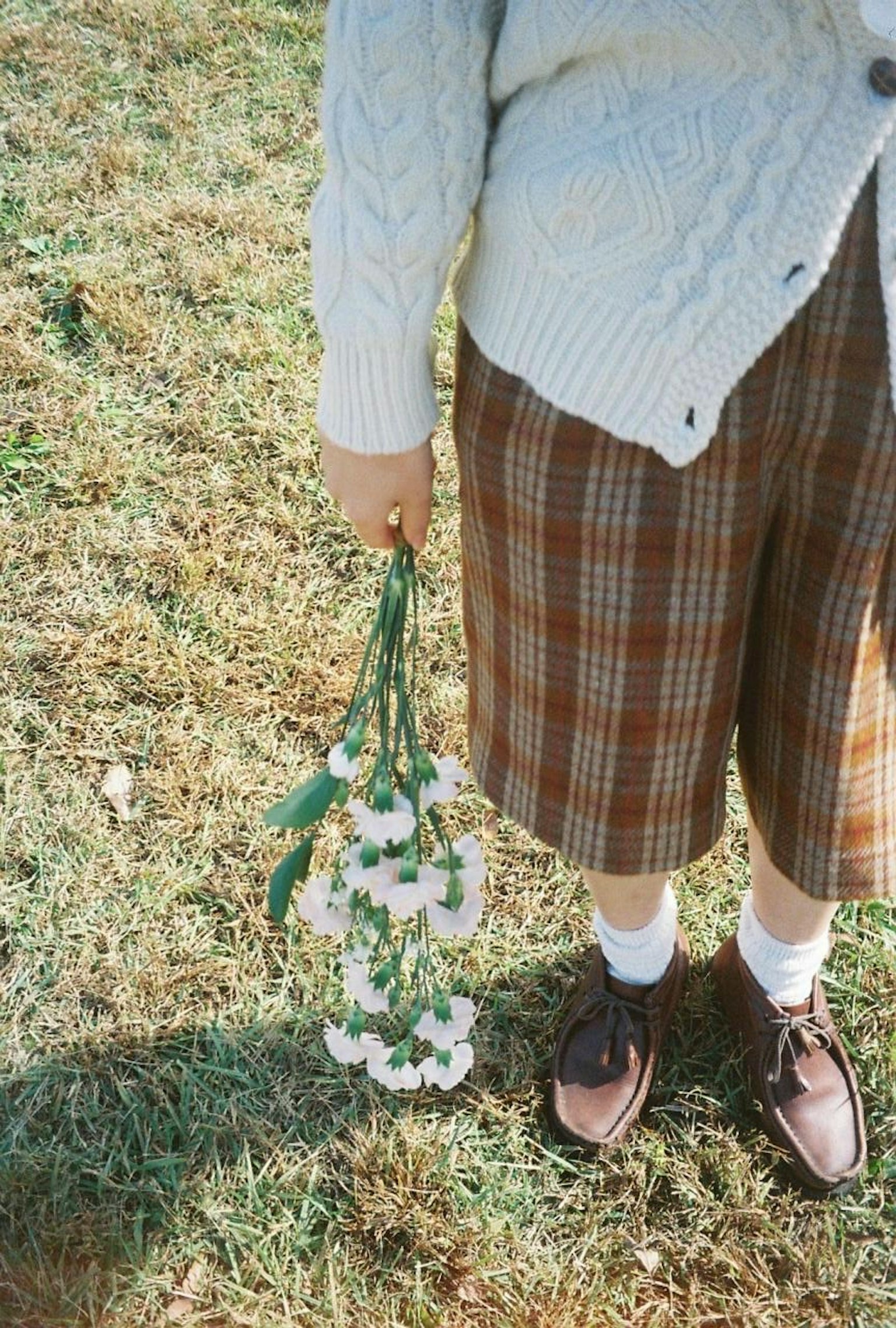 체크무늬 반바지를 입고 흰 꽃다발을 들고 있는 아이