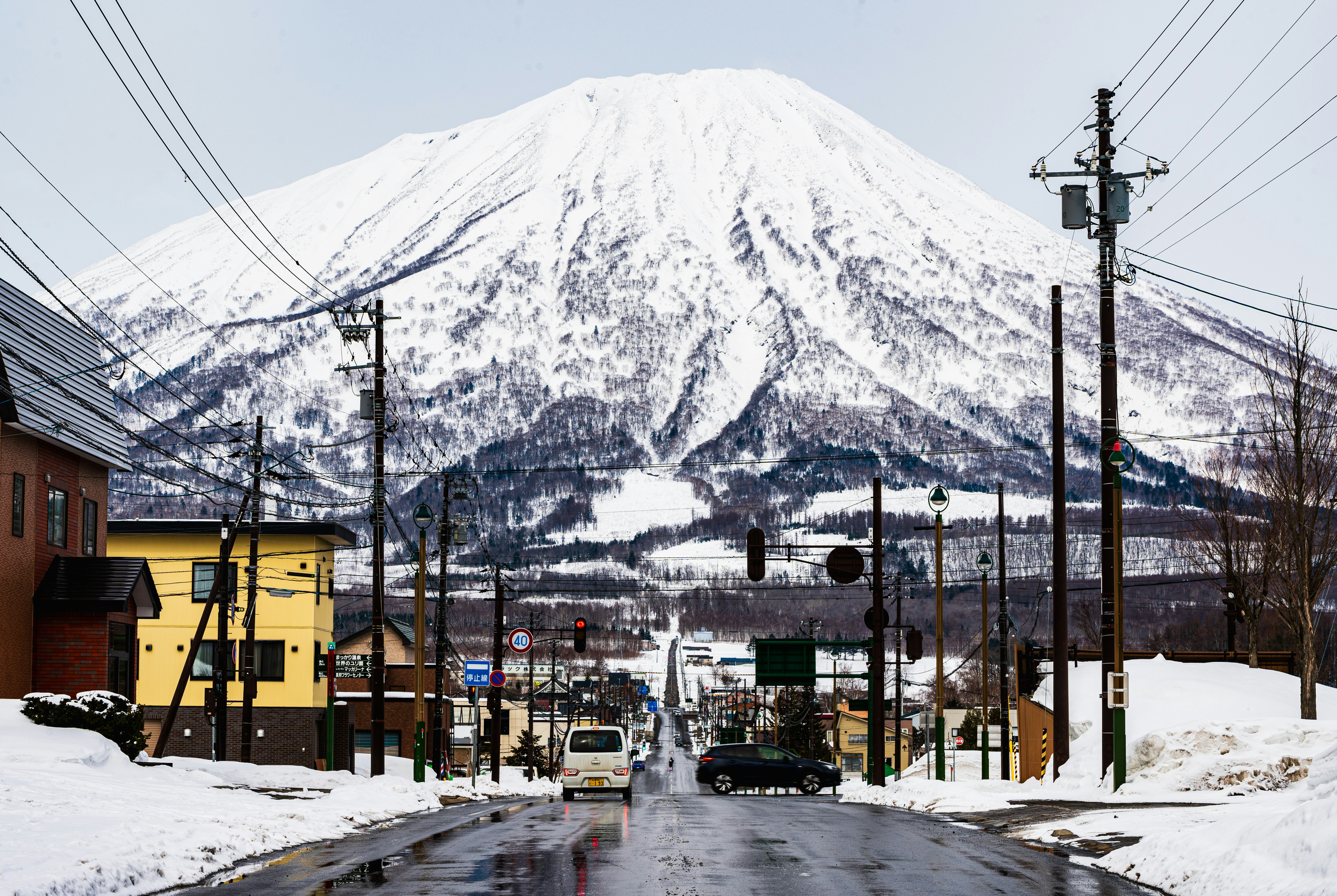 雪をかぶった山と小さな町の通りの風景