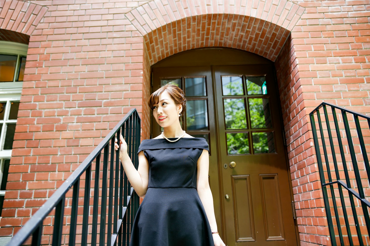 一位穿着黑色裙子的女性站在砖砌建筑前
