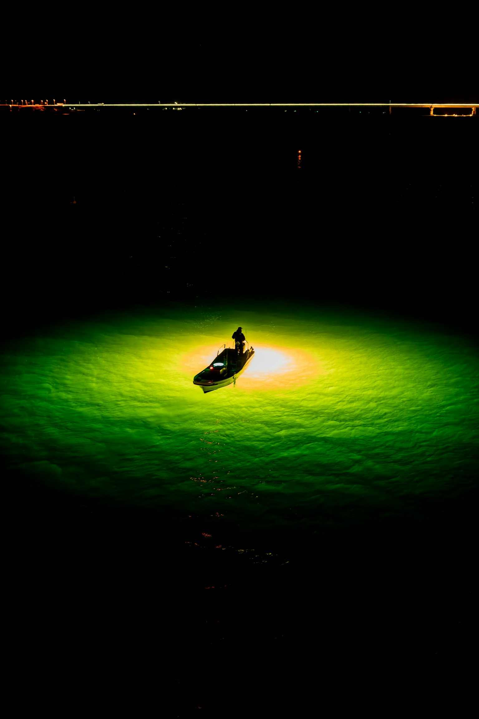 Un pequeño bote iluminado por luz verde sobre una superficie de agua oscura