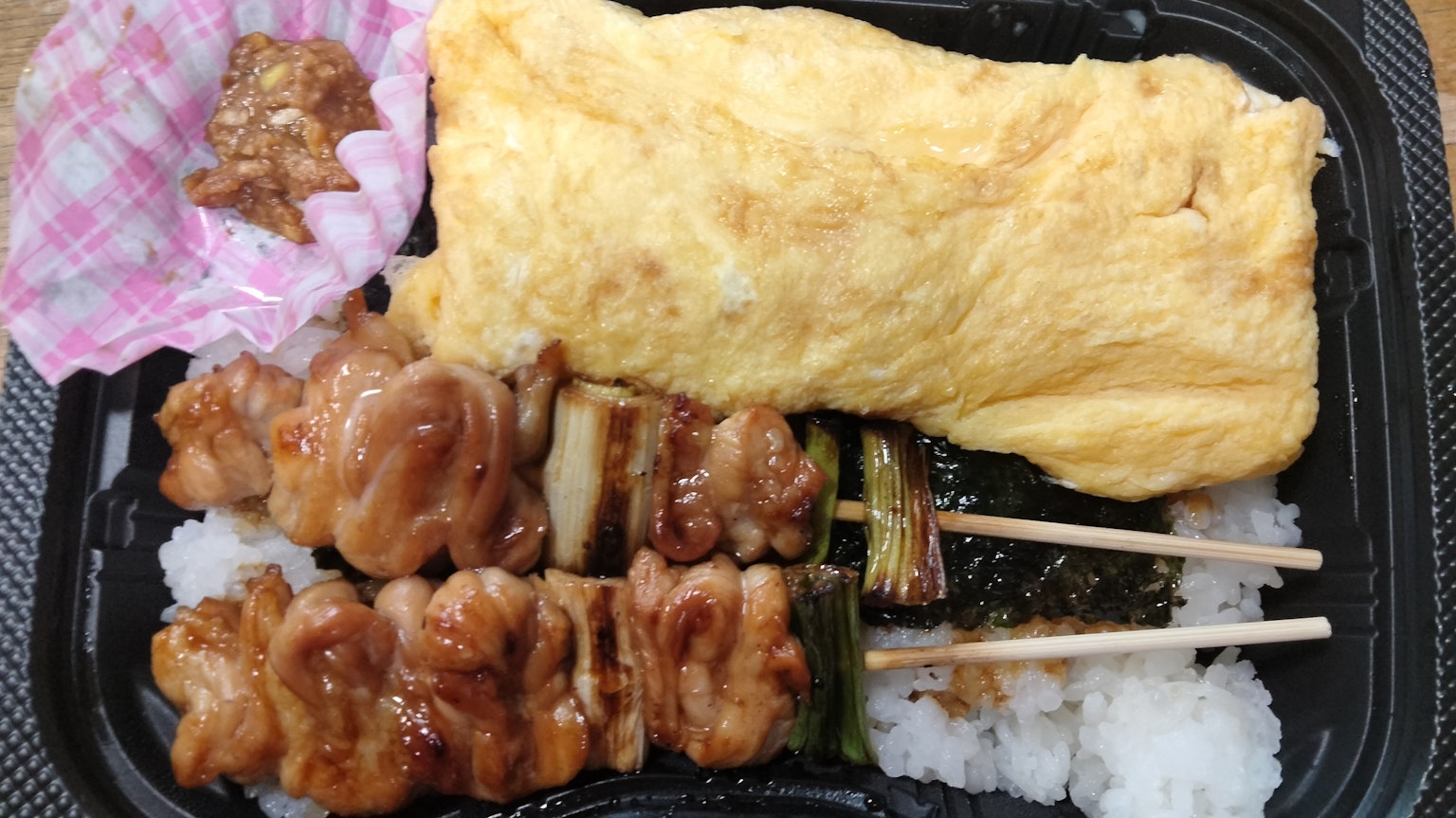 Bento-Box mit gegrillten Hähnchenspießen und einem Omelett serviert mit Reis