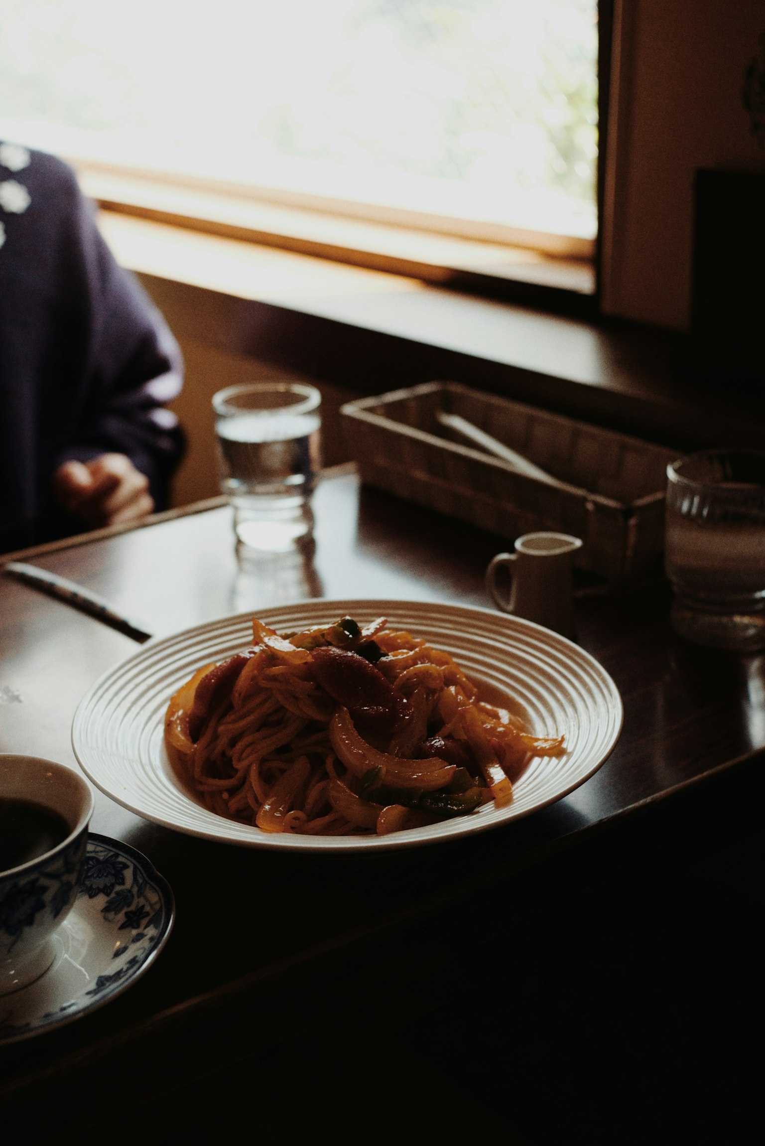 Une assiette de pâtes sur une table avec des verres d'eau et une ambiance chaleureuse