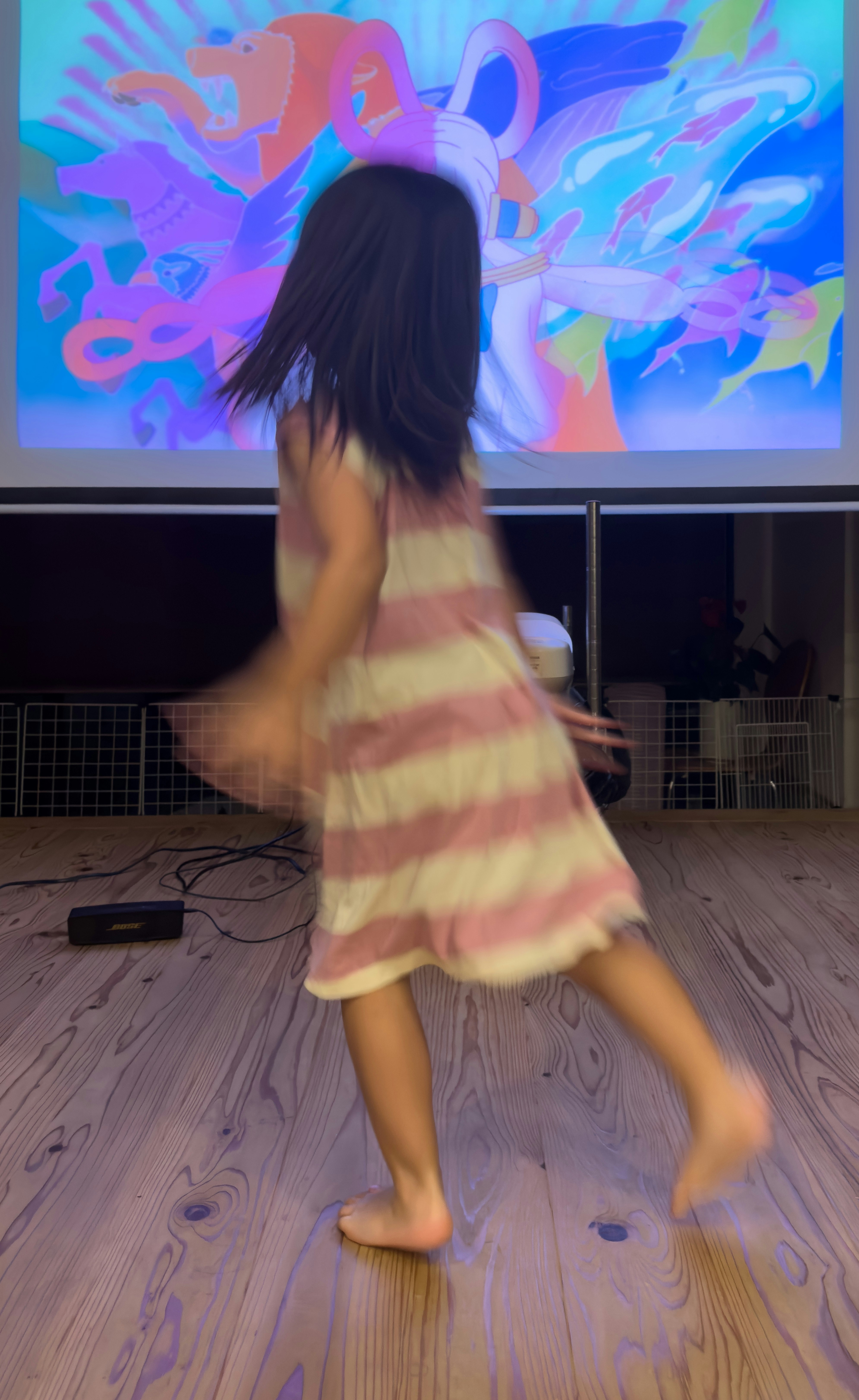 踊る子どもの姿とカラフルな壁面プロジェクションのある室内空間