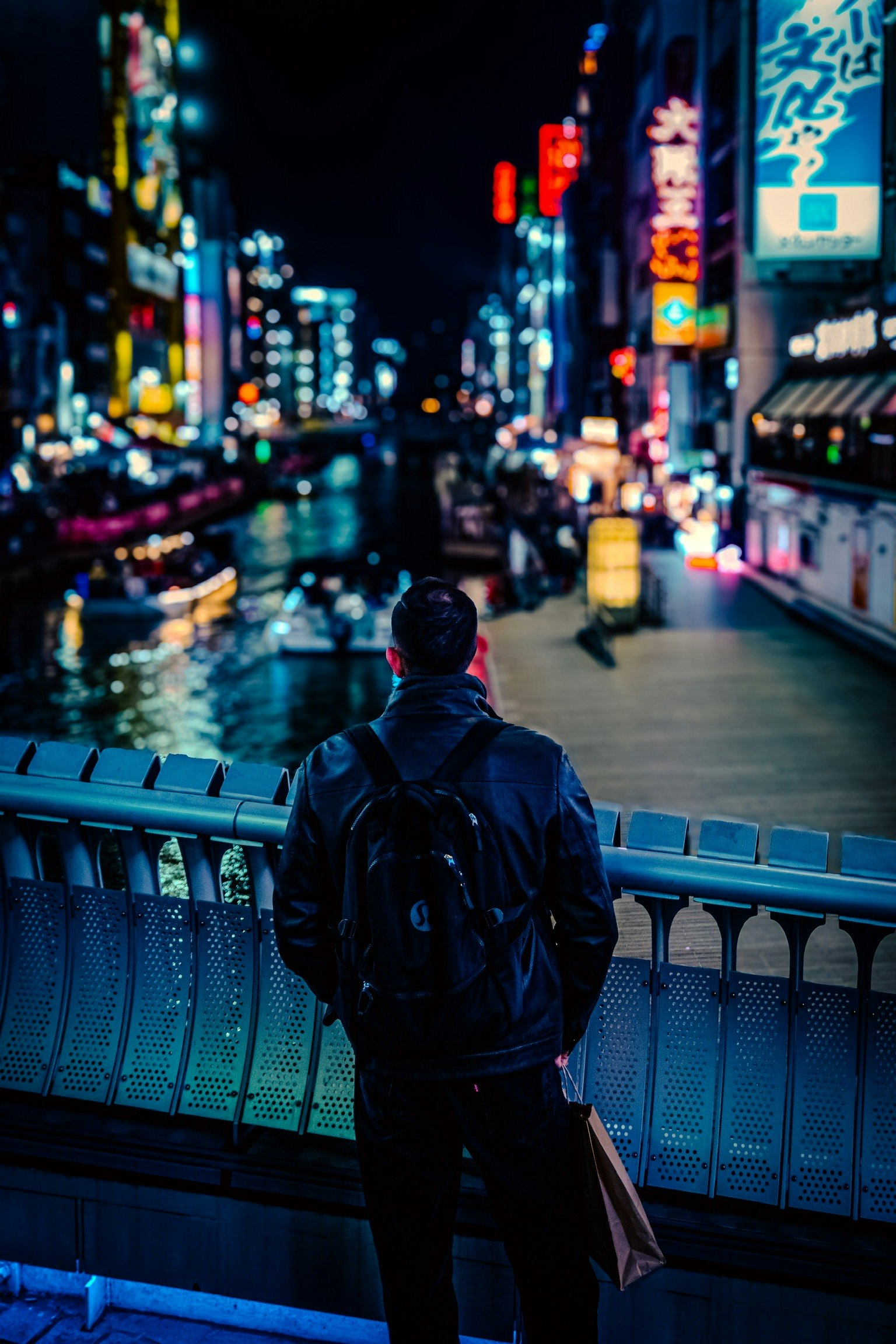 難波の夜のネオンが映る川沿いの通り