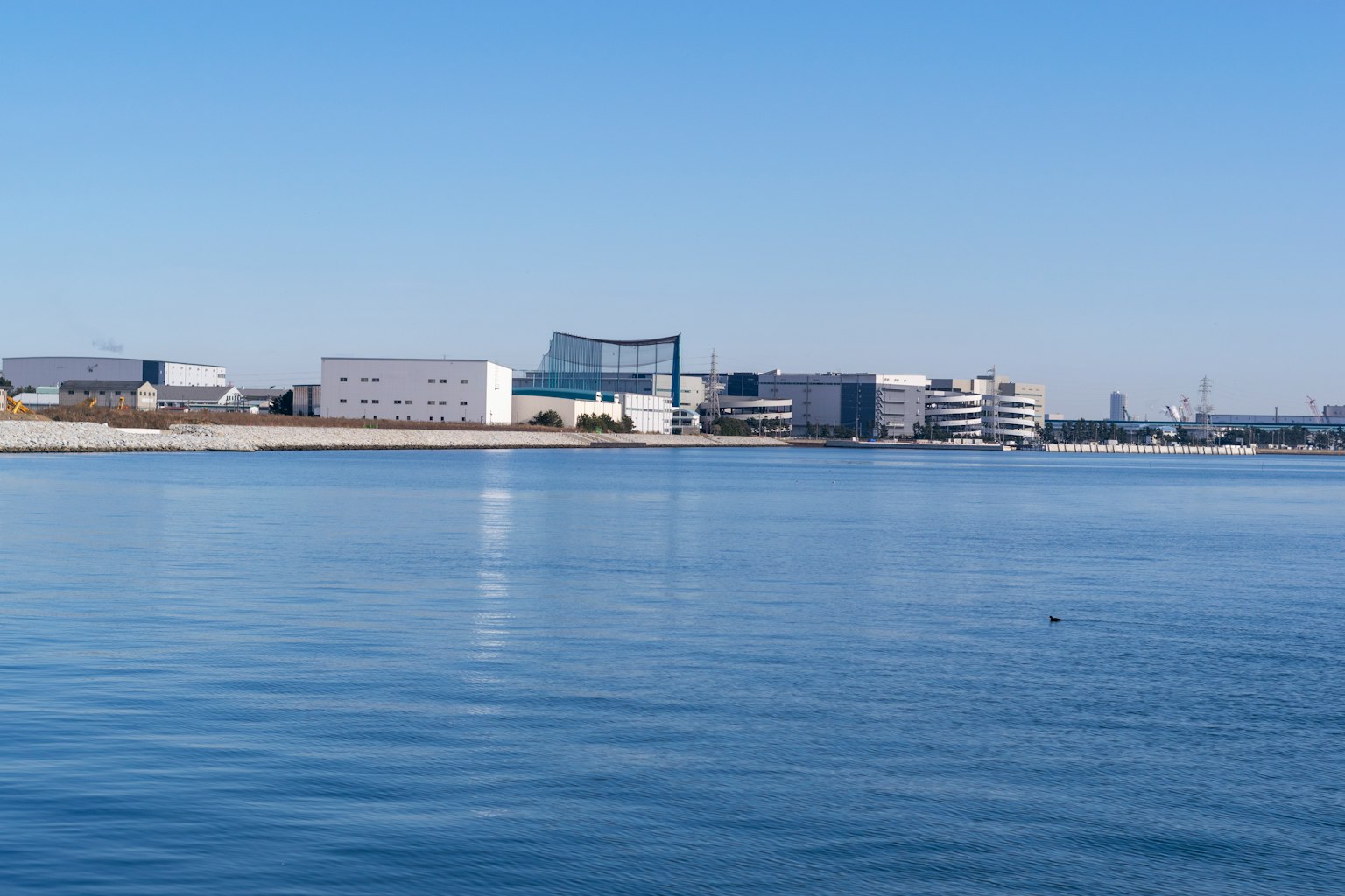 Industriegebiet, das sich im ruhigen Wasser unter einem klaren blauen Himmel spiegelt