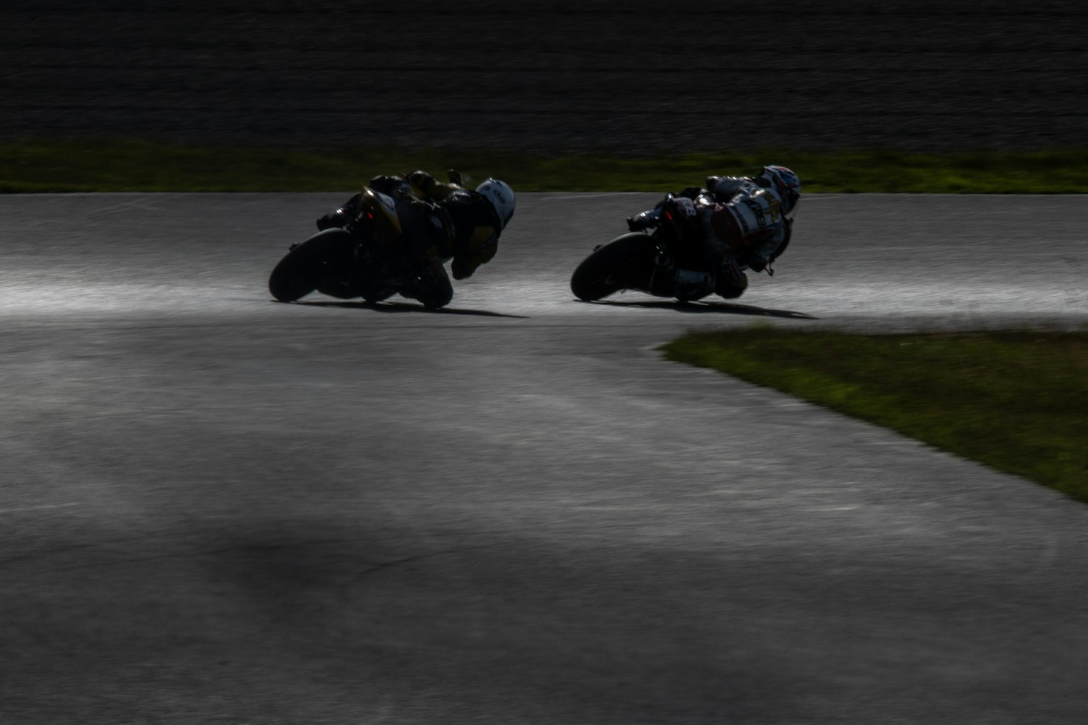 Two motorcycles leaning into a curve during a race
